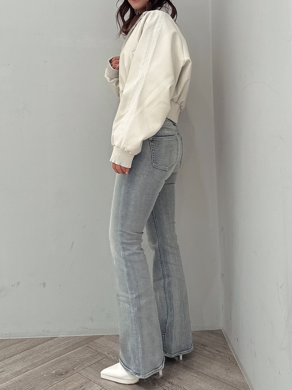 ホワイト系のブルゾン、ブラック系のニット/セーター、ブルー系のデニムパンツを着用したレディースの冬コーディネートの2枚目の写真