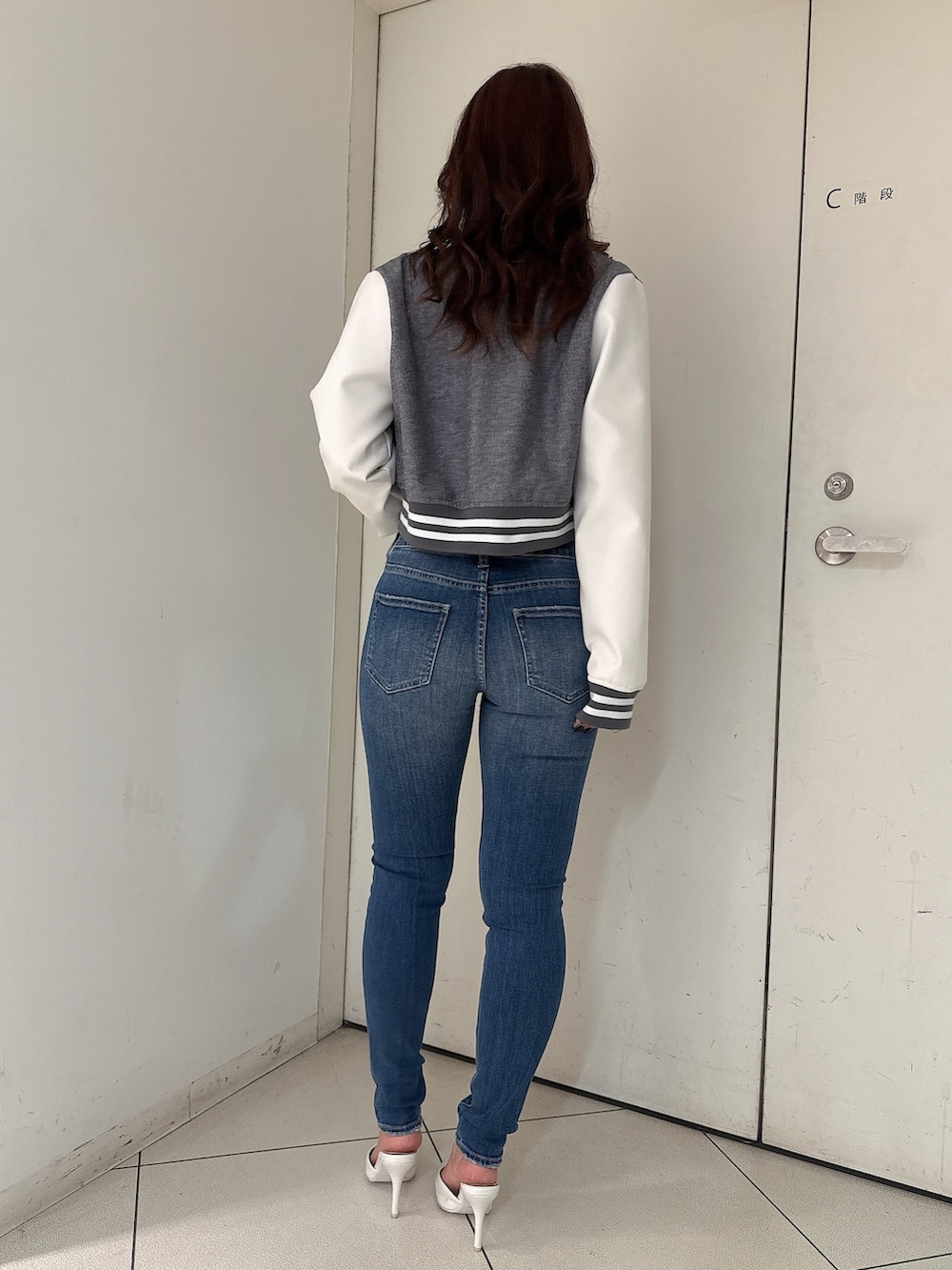 グレー系のニット/セーター、ブルー系のデニムパンツ、ホワイト系のパンプスを着用したレディースの冬コーディネートの3枚目の写真