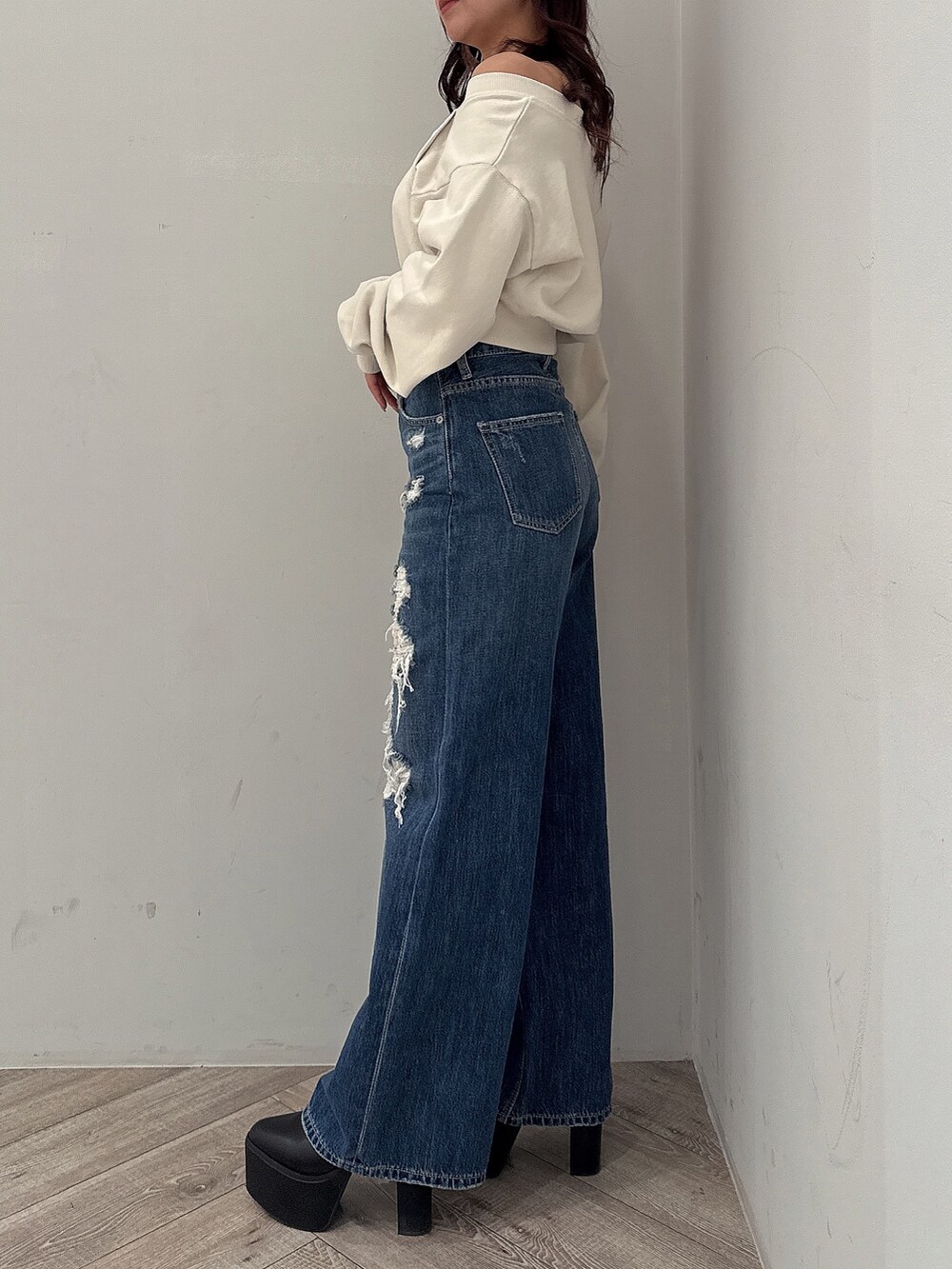 ホワイト系のスウェット、ブルー系のデニムパンツ、ブラック系のブーツを着用したレディースの秋コーディネートの2枚目の写真