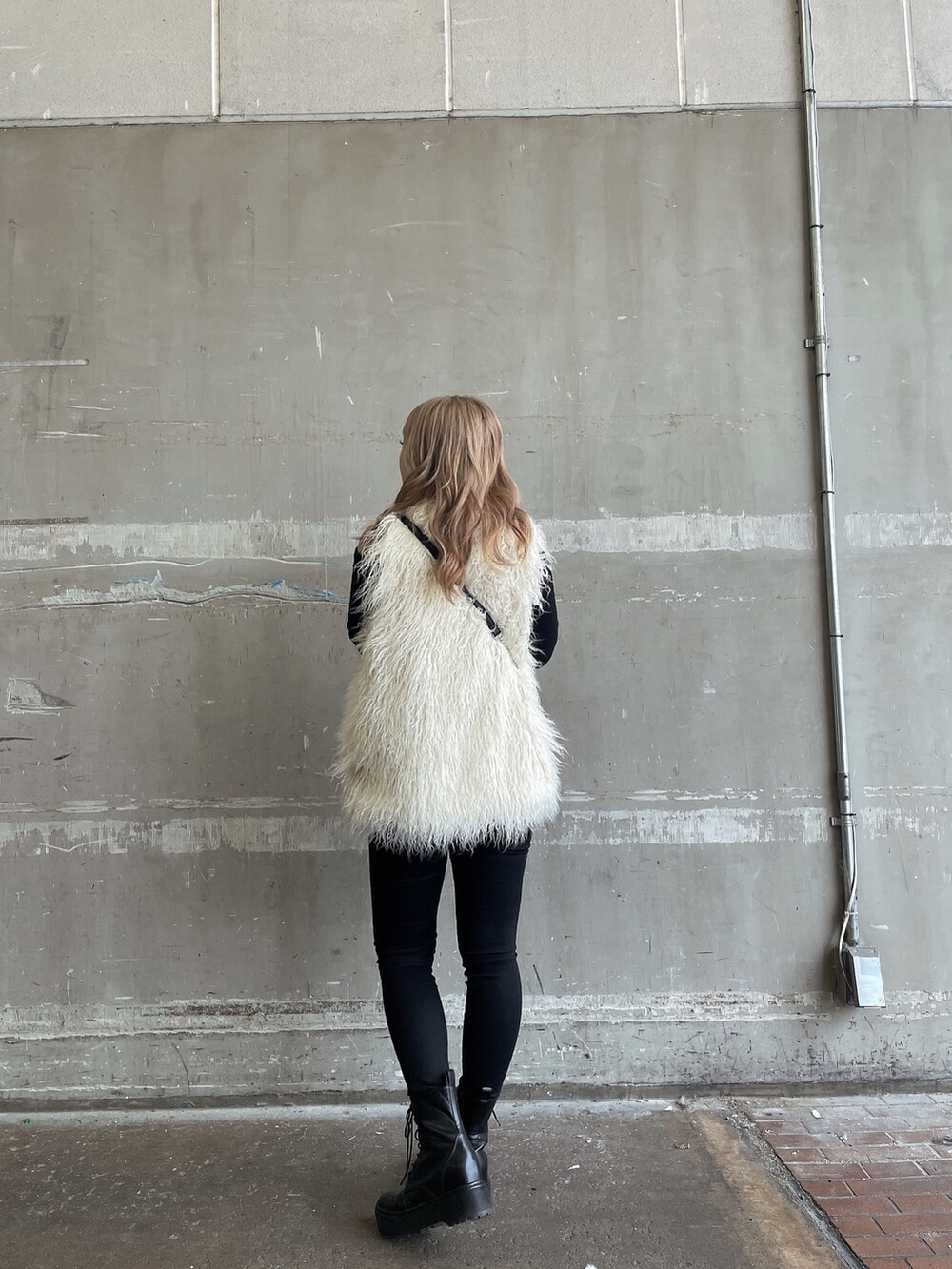 ブラック系のTシャツ/カットソー、ホワイト系のベスト、ブラック系のデニムパンツを着用したレディースの秋コーディネートの2枚目の写真