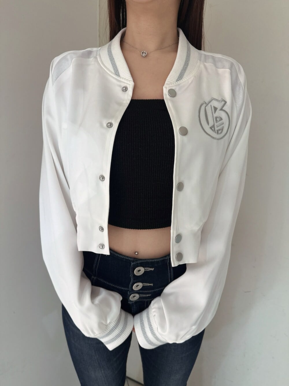 ブルー系のデニムパンツ、ブラック系のサンダル、ホワイト系のブルゾンを着用したレディースの春コーディネートの8枚目の写真