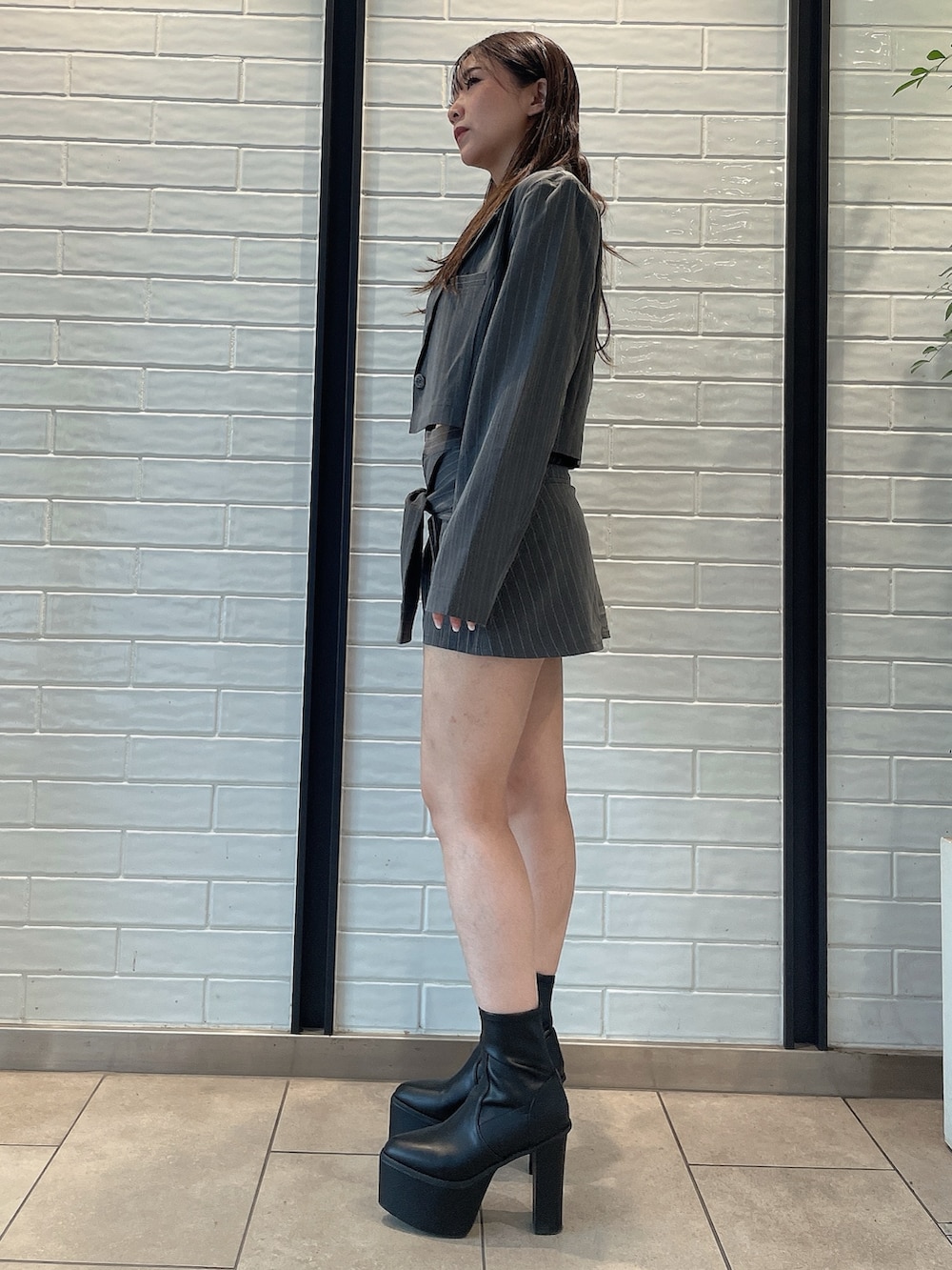 グレー系のスカート、ブラック系のブーツ、グレー系のテーラードジャケットを着用したレディースの夏コーディネートの2枚目の写真
