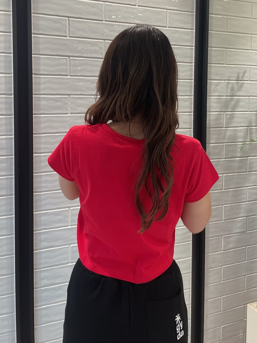 レッド系のTシャツ/カットソー、ブラック系のスウェットパンツ、ホワイト系のスニーカーを着用したレディースの夏コーディネートの5枚目の写真