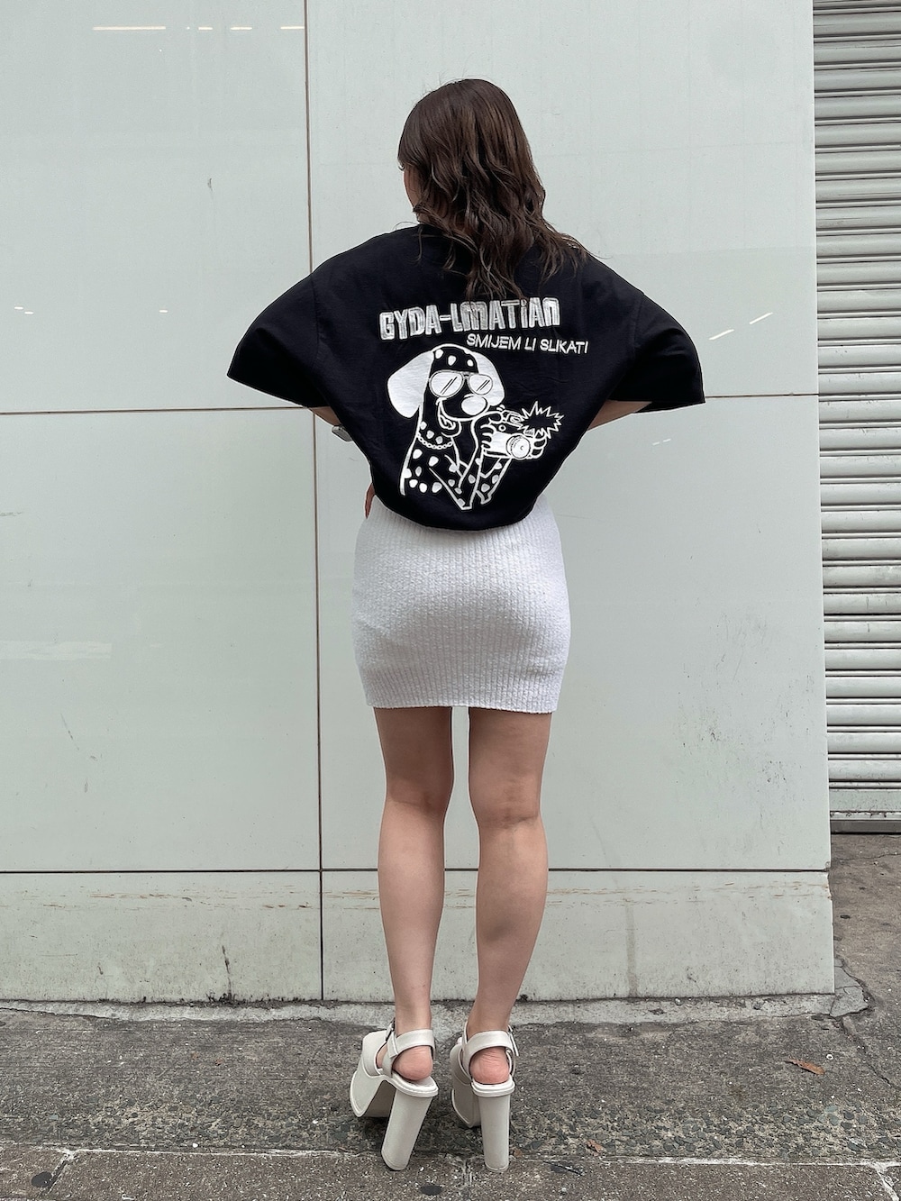 ブラック系のTシャツ/カットソー、ホワイト系のスカート、ホワイト系のサンダルを着用したレディースの春コーディネートの2枚目の写真