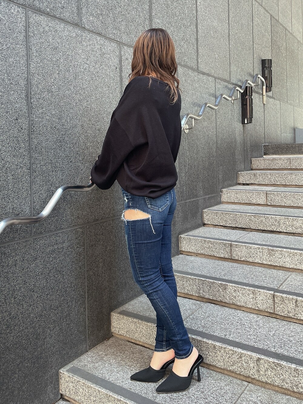 ブラック系のニット/セーター、ブルー系のデニムパンツ、ブラック系のパンプスを着用したレディースの冬コーディネートの2枚目の写真