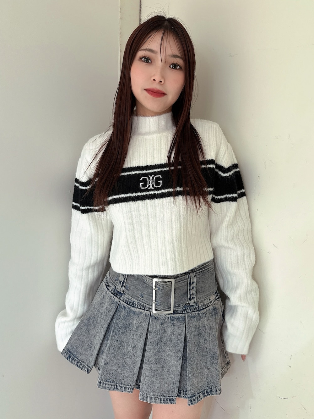 ブルー系のデニムスカート、ブラック系のブーツ、ホワイト系のニット/セーターを着用したレディースの冬コーディネートの4枚目の写真