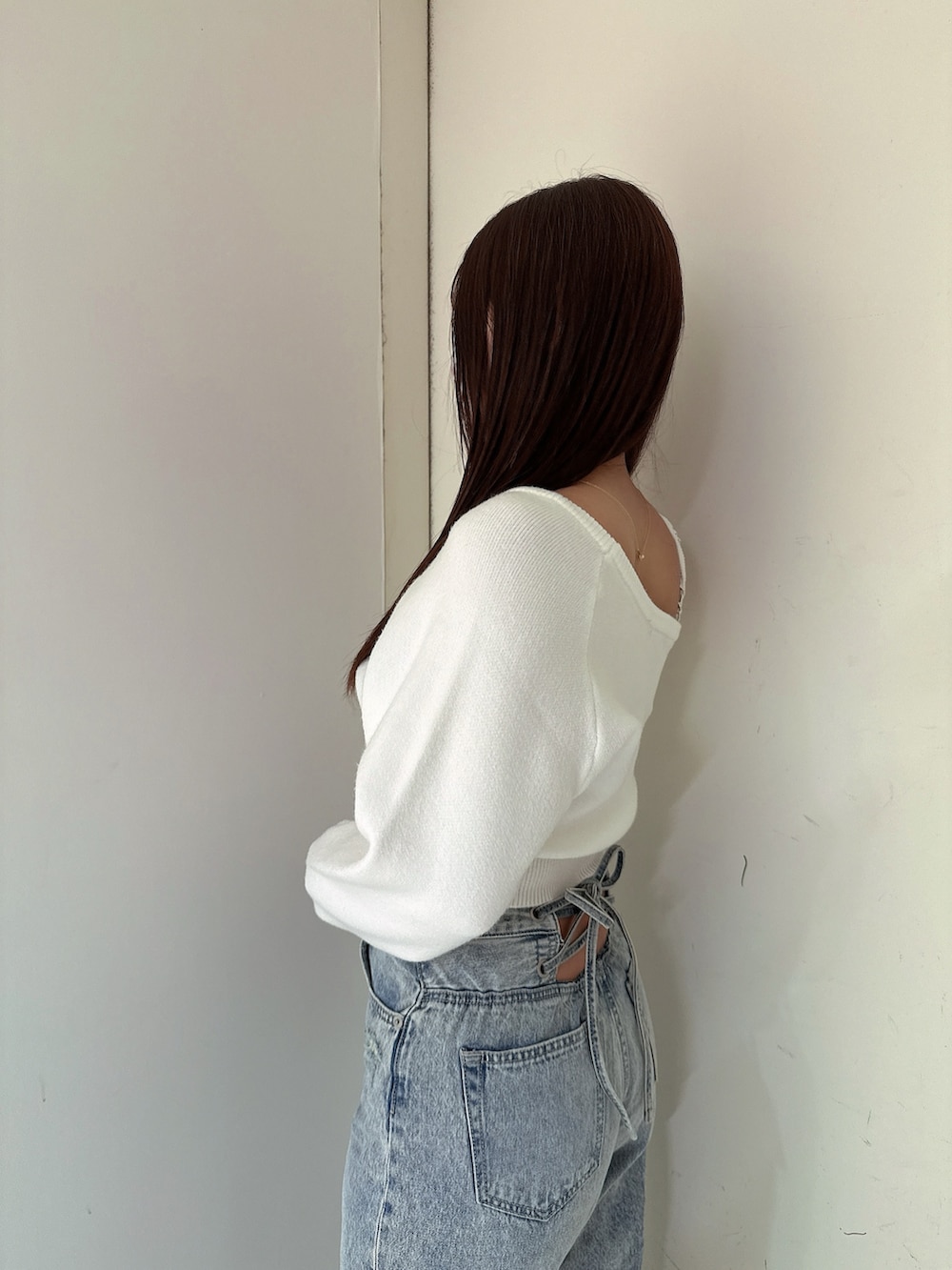 ホワイト系のニット/セーター、ブルー系のデニムパンツ、ホワイト系のパンプスを着用したレディースの冬コーディネートの5枚目の写真