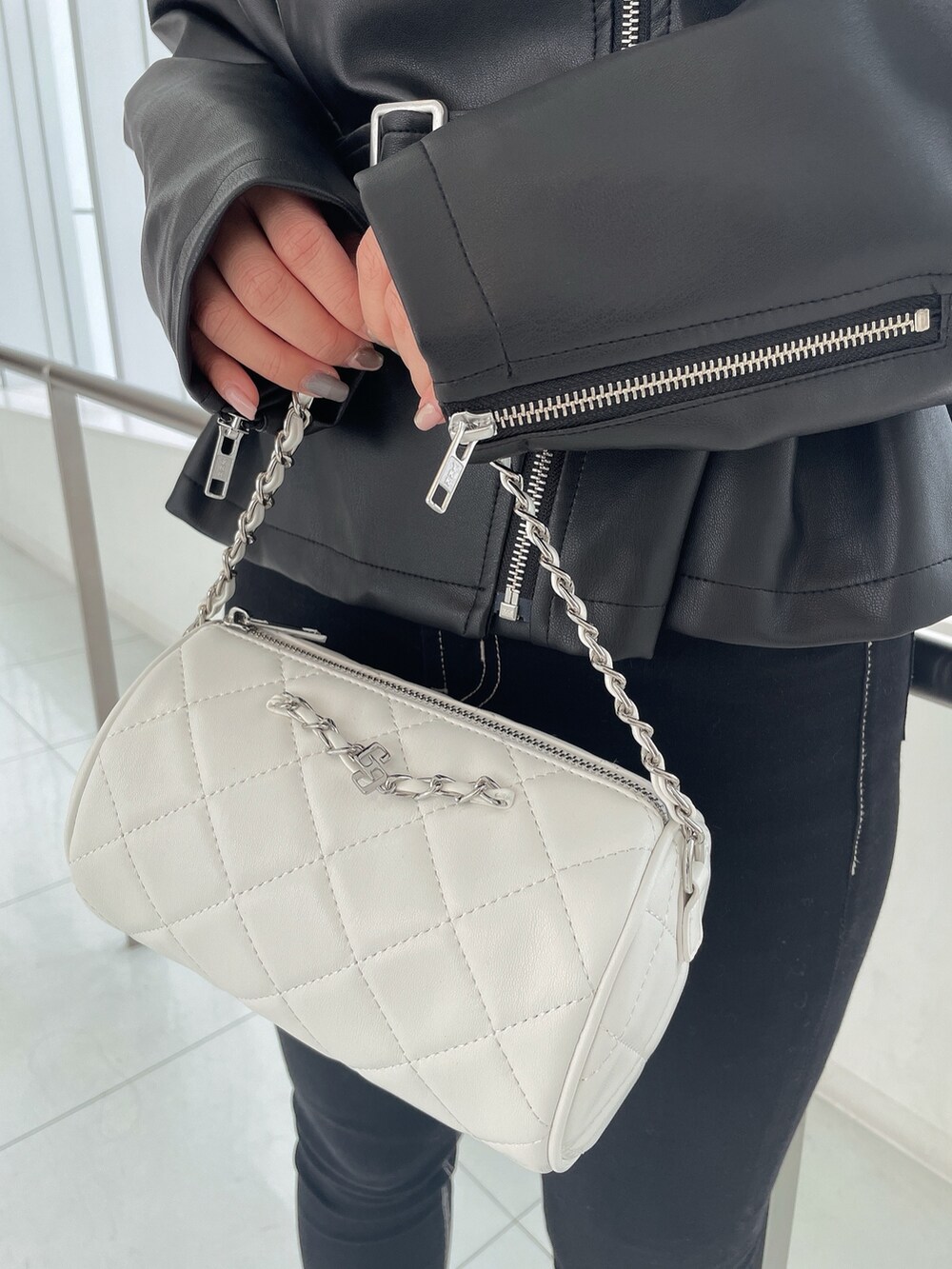 ブラック系のライダースジャケット、ブラック系のデニムパンツ、ホワイト系のハンドバッグを着用したレディースの冬コーディネートの6枚目の写真