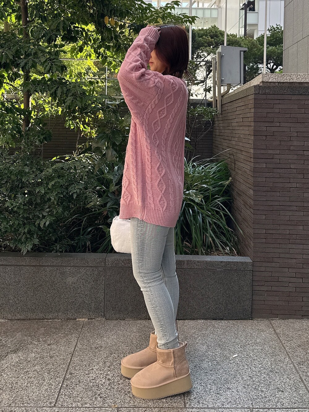 ピンク系のニット/セーター、ホワイト系のハンドバッグ、ブルー系のデニムパンツを着用したレディースの秋コーディネートの2枚目の写真