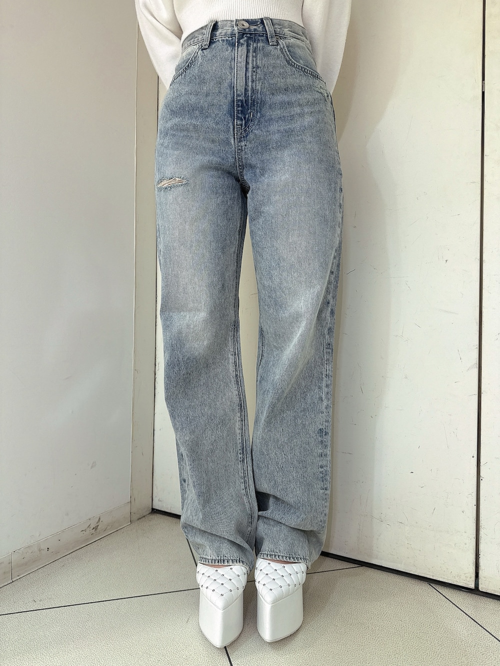 ホワイト系のニット/セーター、ブルー系のデニムパンツ、ホワイト系のパンプスを着用したレディースの冬コーディネートの8枚目の写真