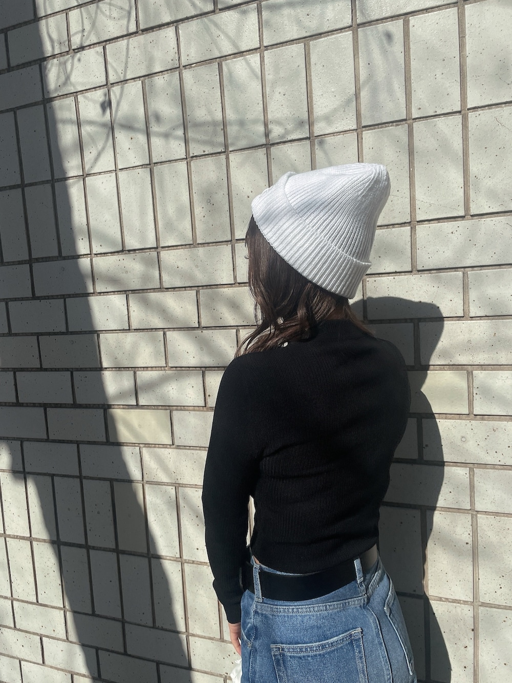 ブラック系のニット/セーター、ホワイト系のバックパック/リュック、ブルー系のデニムパンツを着用したレディースの冬コーディネートの5枚目の写真