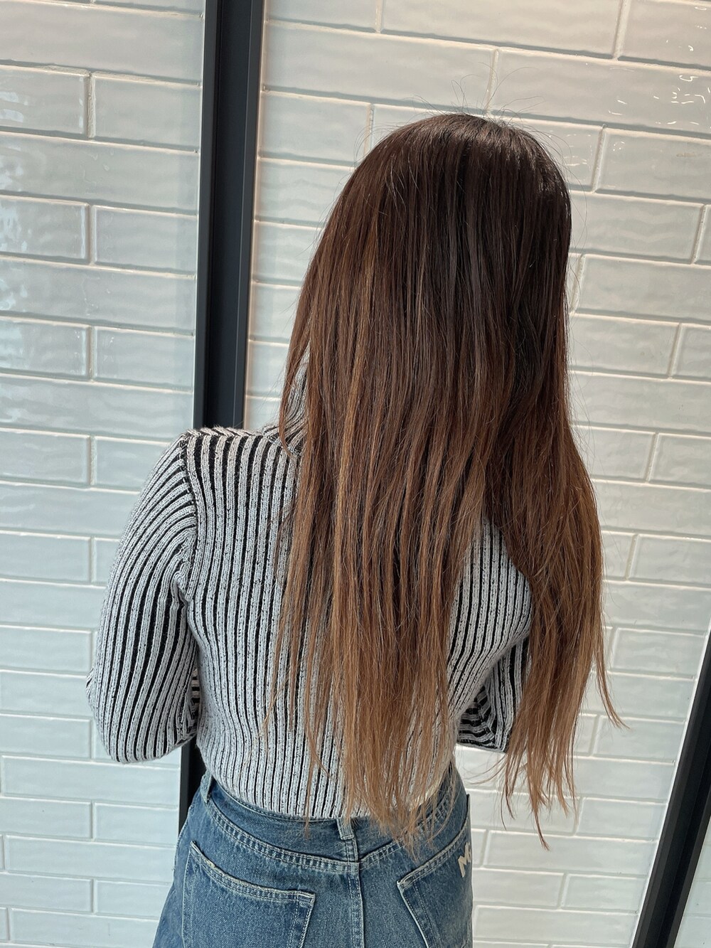 ブラック系のデニムパンツ、ブラック系のブーツ、その他のニット/セーターを着用したレディースの秋コーディネートの6枚目の写真