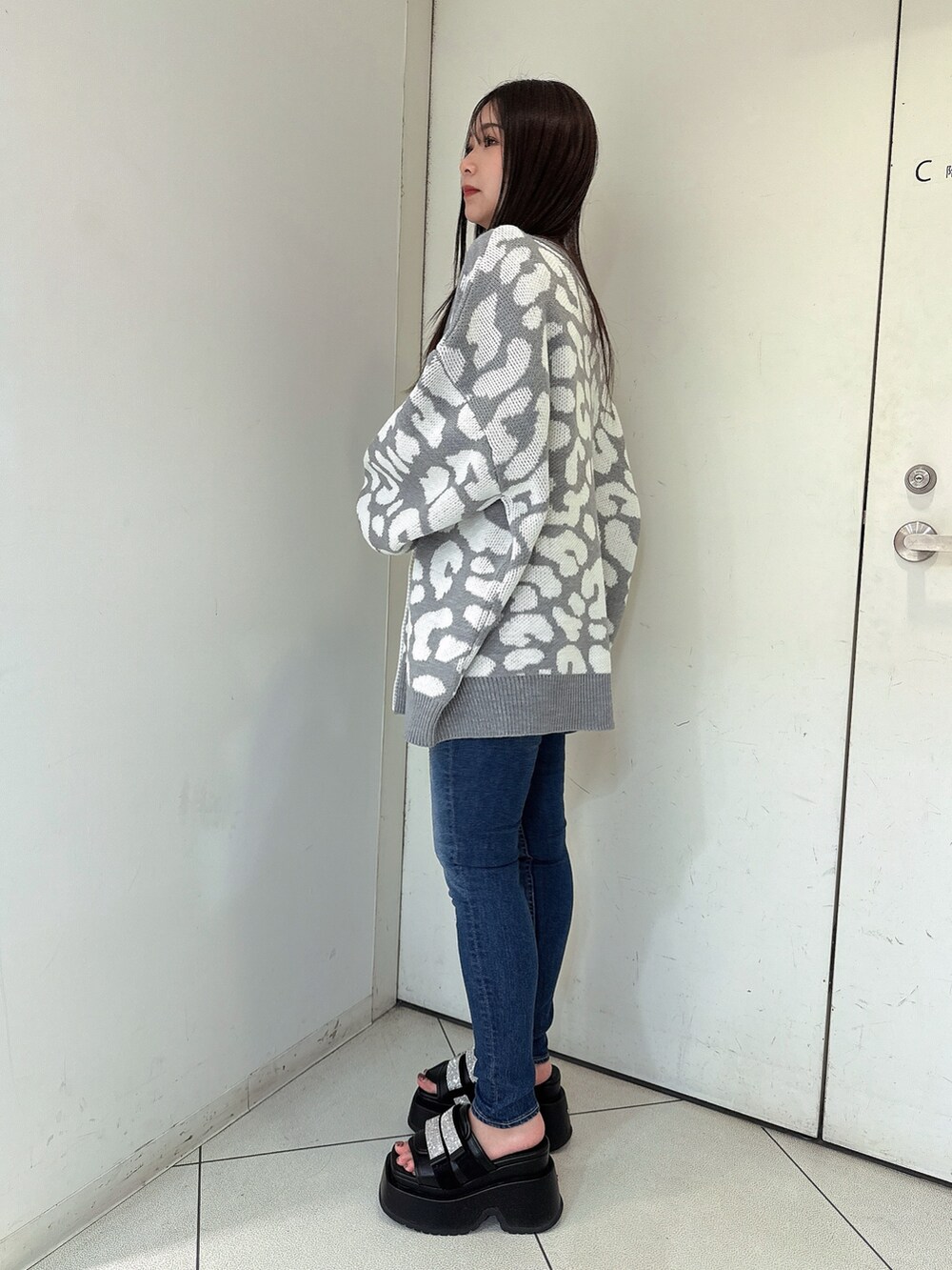 グレー系のカーディガン/ボレロ、ブルー系のデニムパンツ、ブラック系のサンダルを着用したレディースの春コーディネートの2枚目の写真