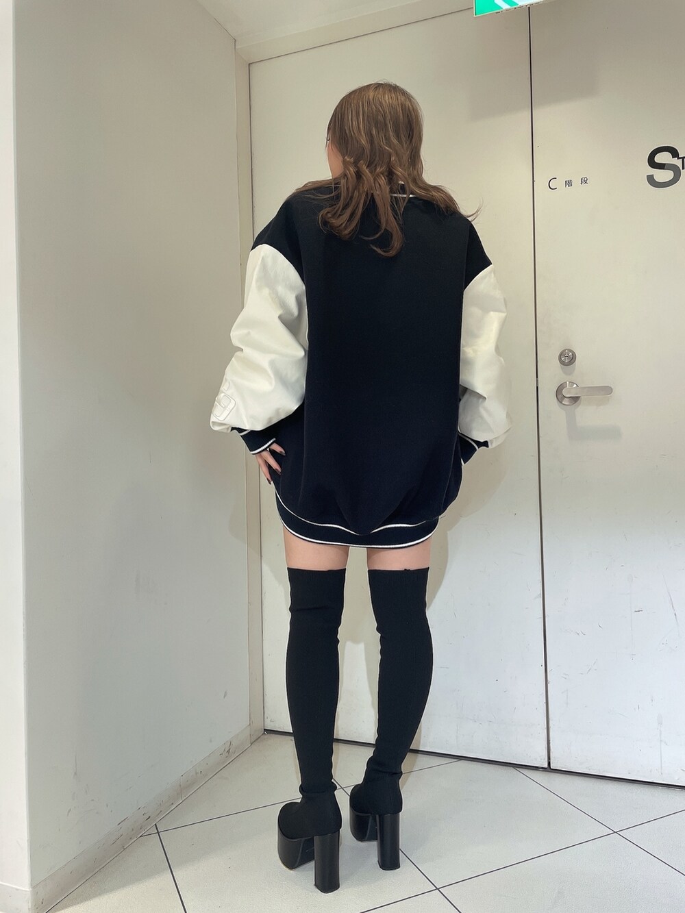ブルー系のスタジャン、ホワイト系のニット/セーター、ブラック系のスカートを着用したレディースの秋コーディネートの4枚目の写真