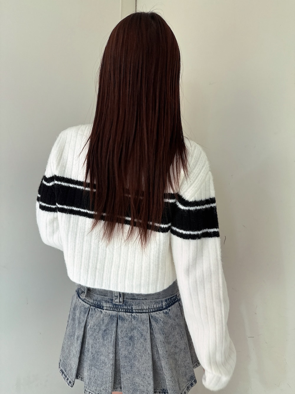 ブルー系のデニムスカート、ブラック系のブーツ、ホワイト系のニット/セーターを着用したレディースの冬コーディネートの6枚目の写真