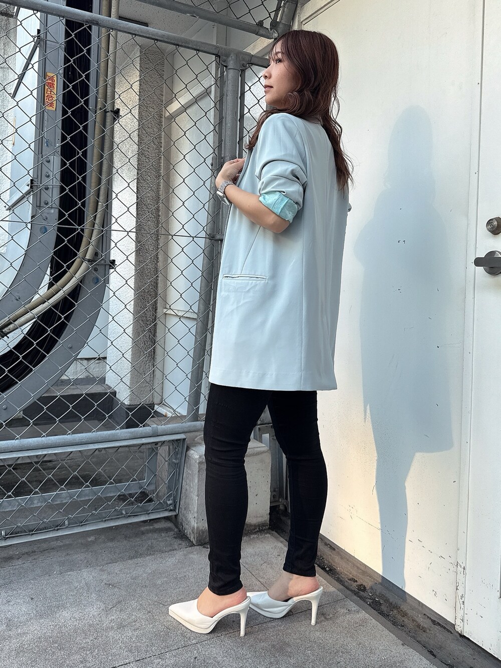 ブラック系のキャミソール、ブラック系のデニムパンツ、ホワイト系のパンプスを着用したレディースの春コーディネートの2枚目の写真