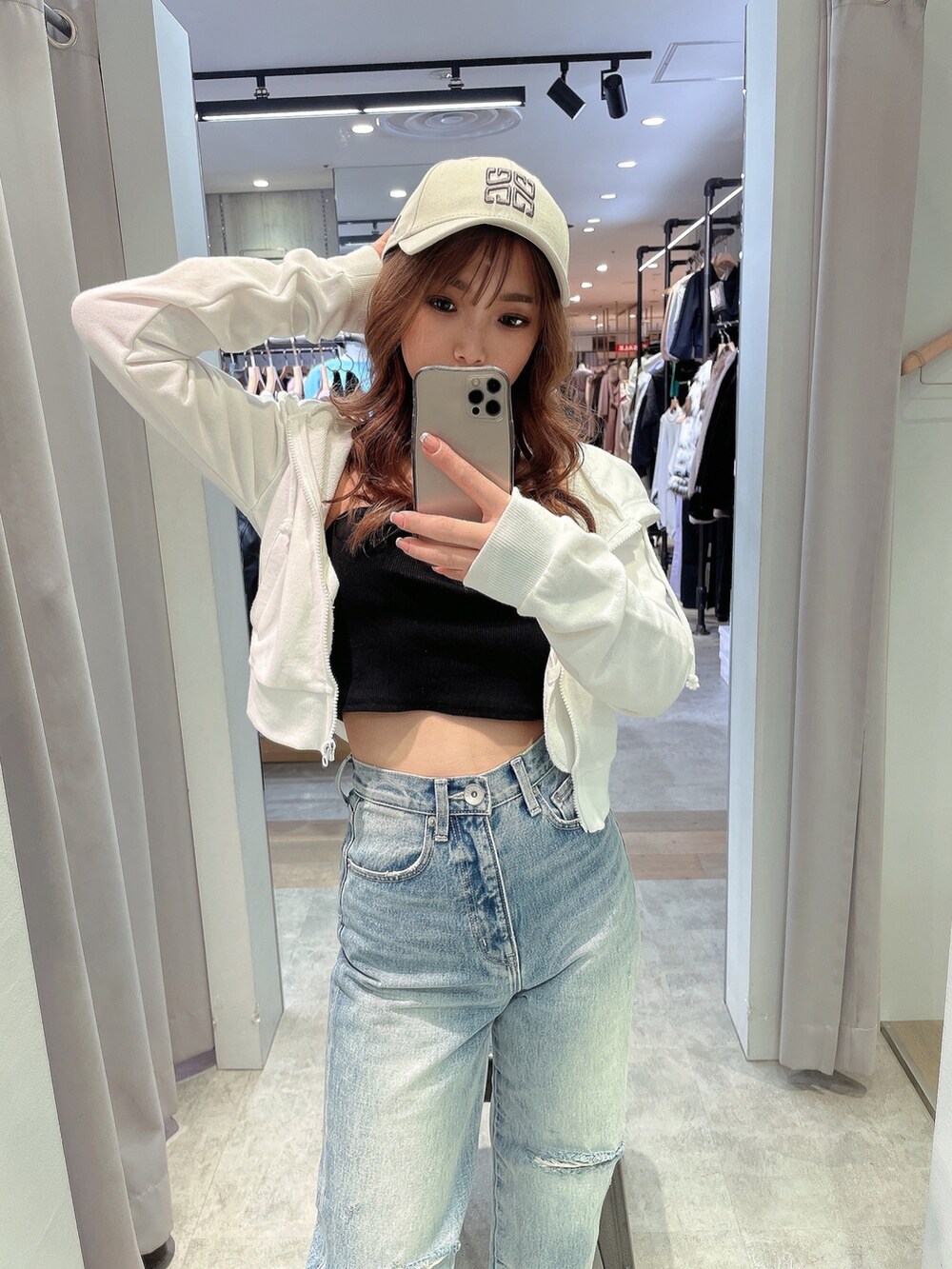 ホワイト系のパーカー、ブラック系のチューブトップ、ブルー系のデニムパンツを着用したレディースの冬コーディネートの4枚目の写真