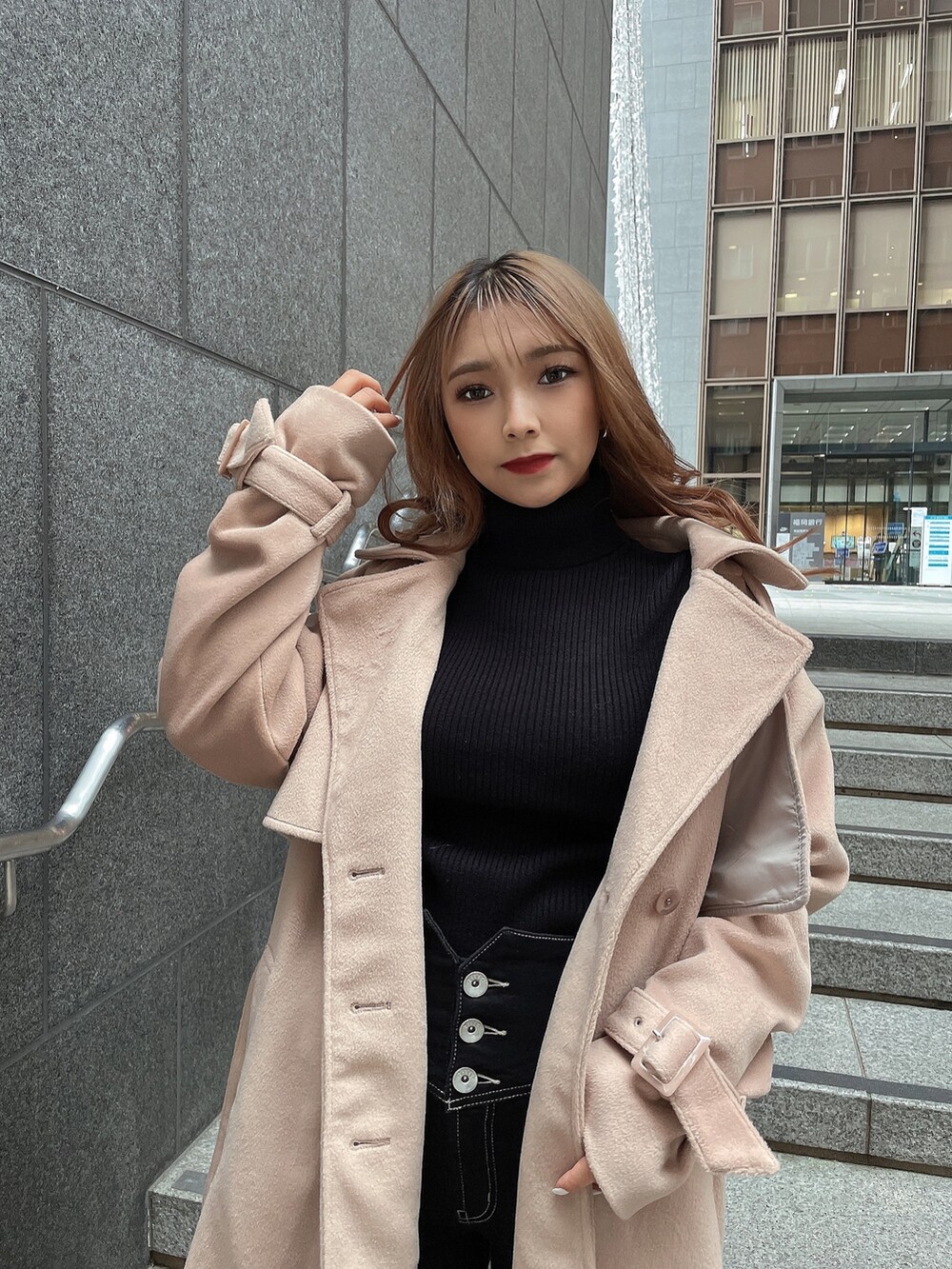 ブラック系のニット/セーター、ベージュ系のトレンチコート、ブラック系のデニムパンツを着用したレディースの冬コーディネートの4枚目の写真