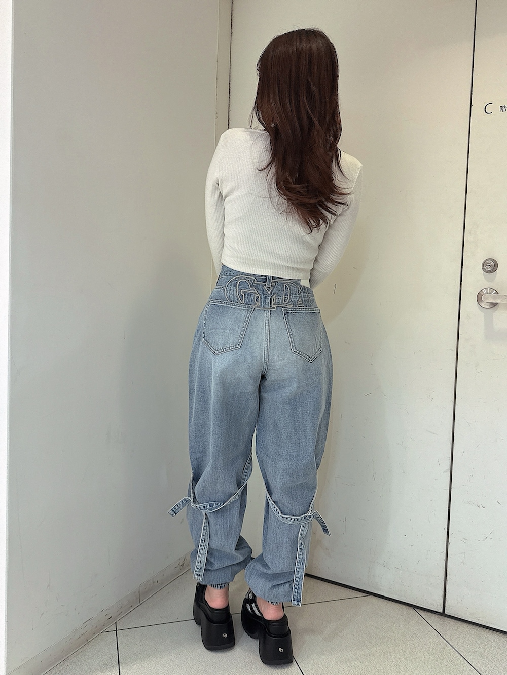 ブルー系のデニムパンツ、ブラック系のサンダル、ホワイト系のTシャツ/カットソーを着用したレディースの春コーディネートの3枚目の写真