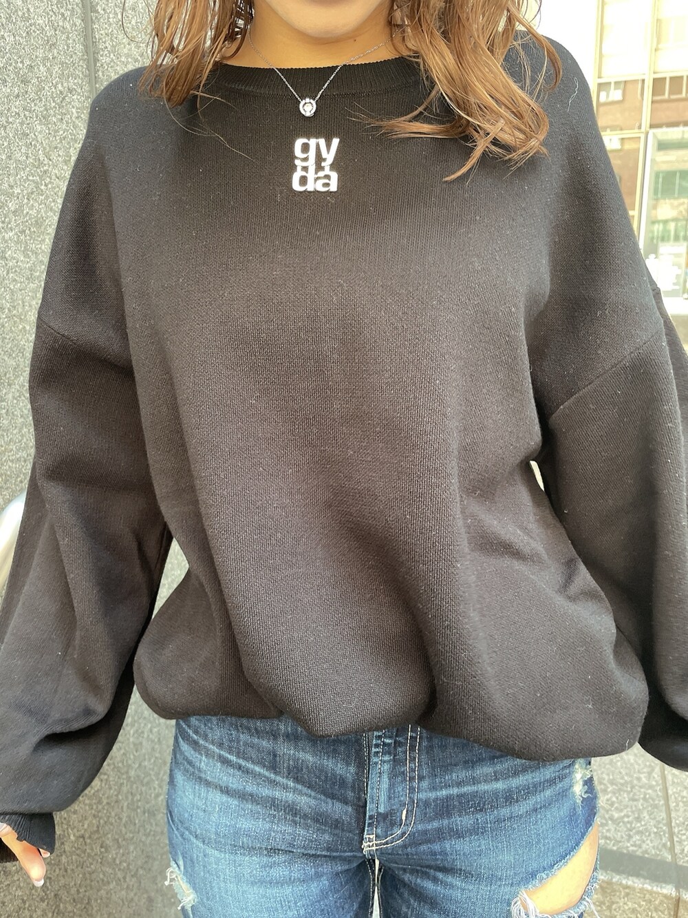 ブラック系のニット/セーター、ブルー系のデニムパンツ、ブラック系のパンプスを着用したレディースの冬コーディネートの6枚目の写真