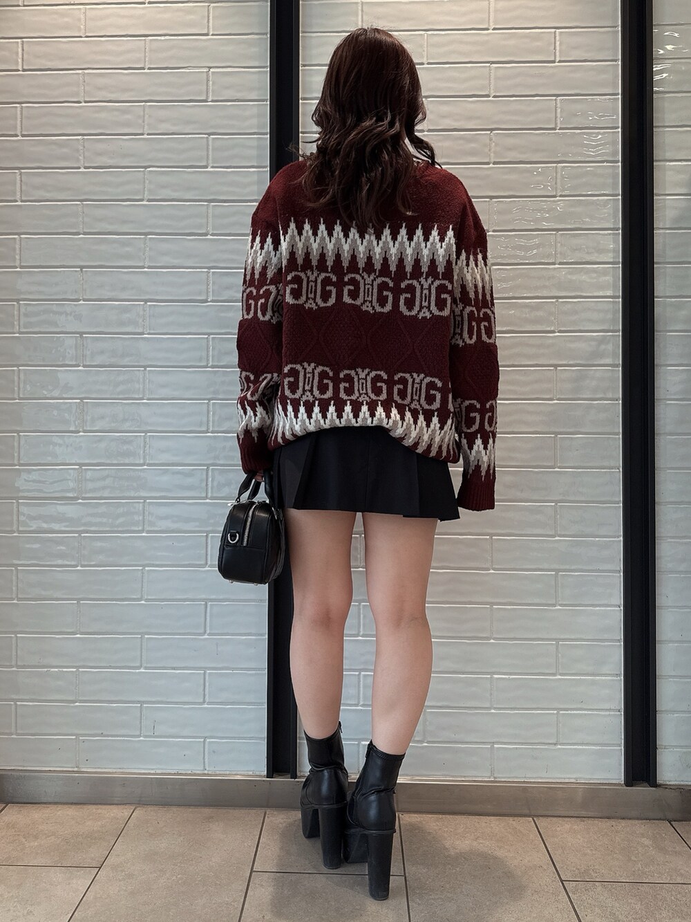 レッド系のニット/セーター、ブラック系のスカート、ブラック系のハンドバッグを着用したレディースの冬コーディネートの3枚目の写真