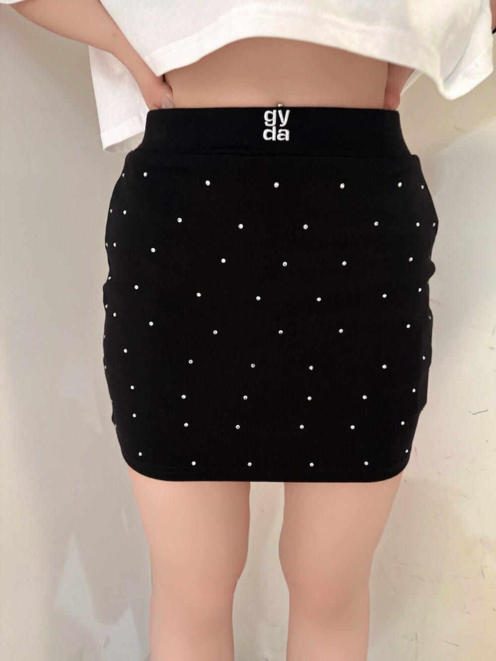 ブラック系のスカート、ホワイト系のTシャツ/カットソー、ブラック系のサンダルを着用したレディースの夏コーディネートの8枚目の写真