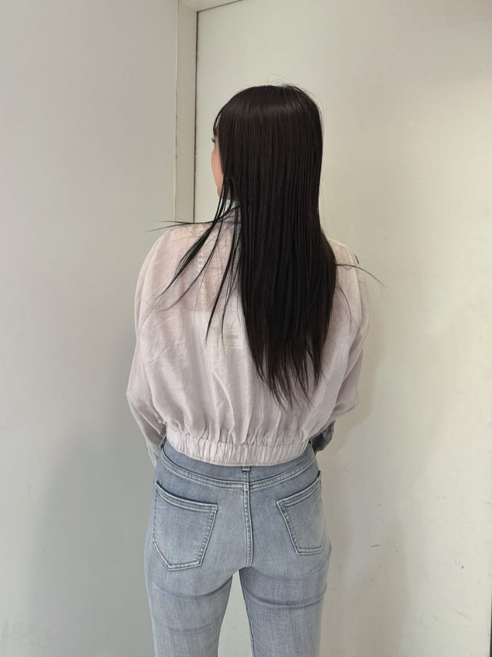 ブルー系のデニムパンツ、ブラック系のサンダル、ホワイト系のブルゾンを着用したレディースの春コーディネートの6枚目の写真