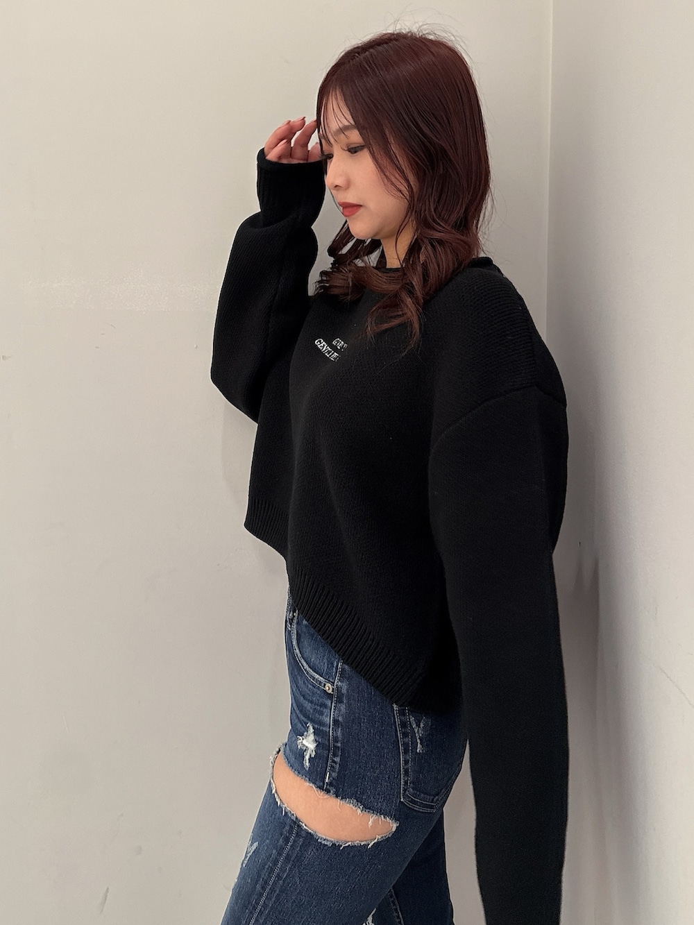 ブラック系のニット/セーター、ブルー系のデニムパンツ、ブラック系のブーツを着用したレディースの秋コーディネートの5枚目の写真