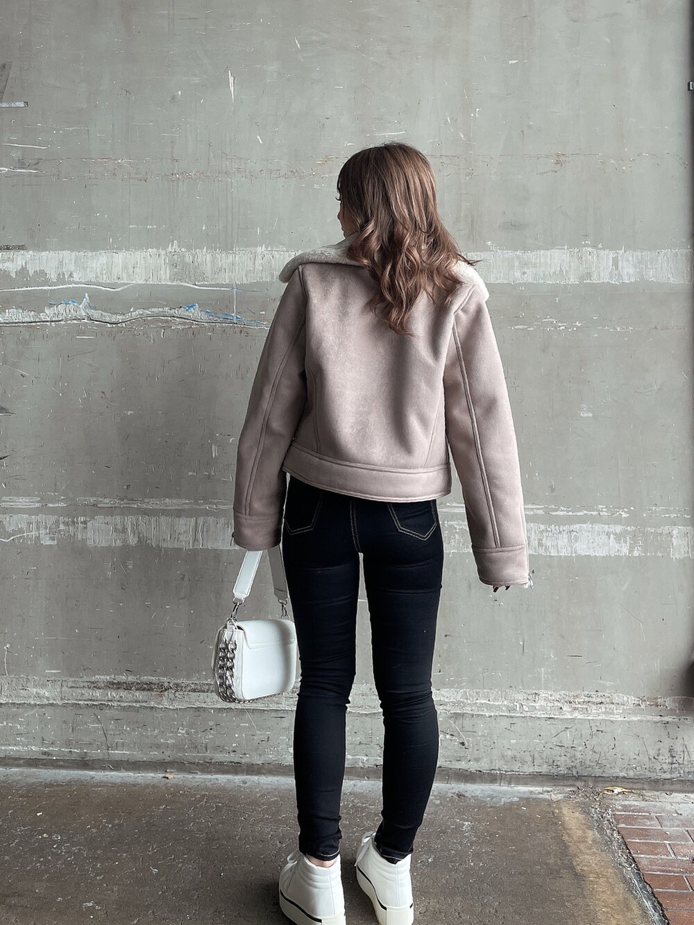 ベージュ系のムートンコート、ホワイト系のTシャツ/カットソー、ホワイト系のハンドバッグを着用したレディースの秋コーディネートの3枚目の写真