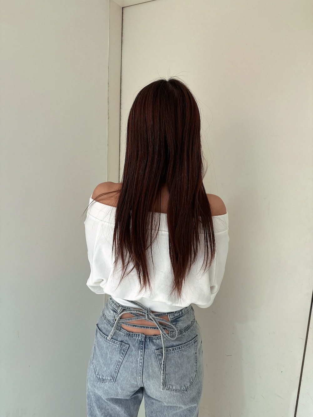 ホワイト系のスウェット、ブルー系のデニムパンツ、ホワイト系のサンダルを着用したレディースの冬コーディネートの6枚目の写真