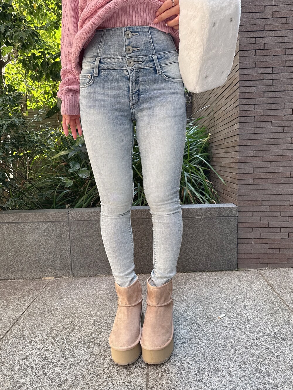 ピンク系のニット/セーター、ホワイト系のハンドバッグ、ブルー系のデニムパンツを着用したレディースの秋コーディネートの9枚目の写真