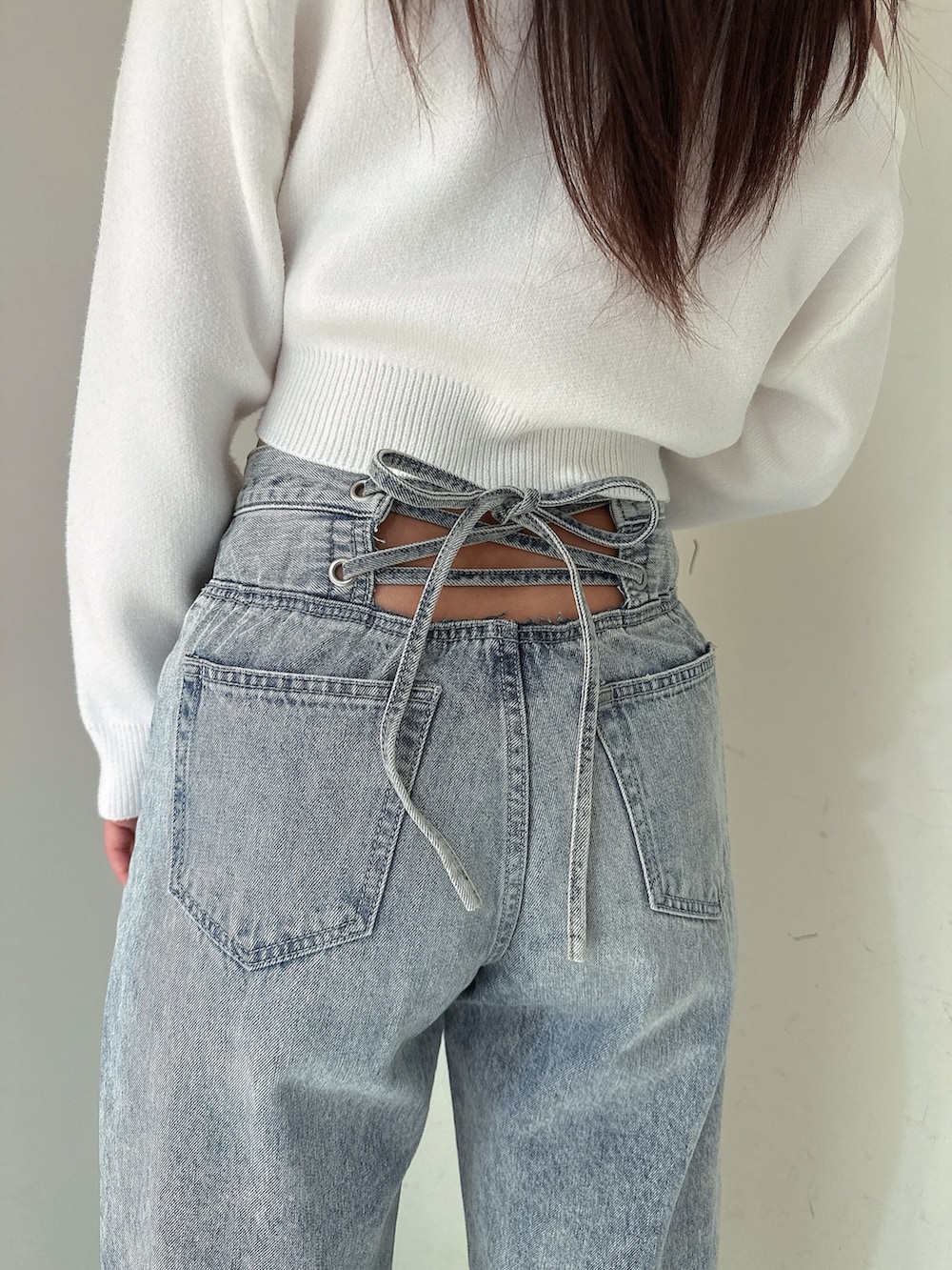 ホワイト系のニット/セーター、ブルー系のデニムパンツ、ホワイト系のパンプスを着用したレディースの冬コーディネートの9枚目の写真