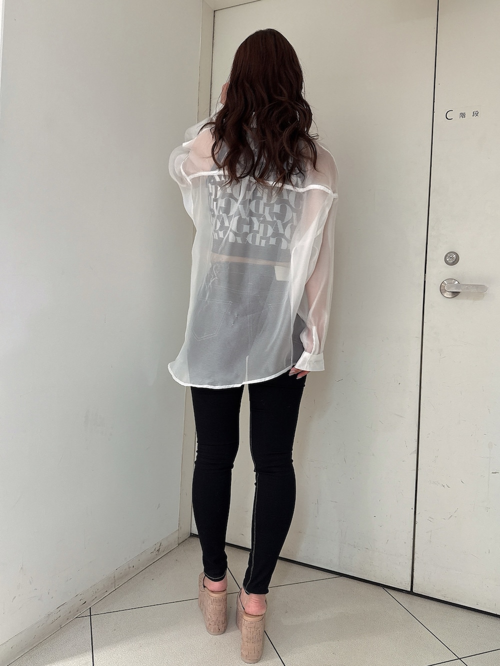 ブラック系のニット/セーター、ブラック系のデニムパンツ、ホワイト系のシャツ/ブラウスを着用したレディースの春コーディネートの3枚目の写真