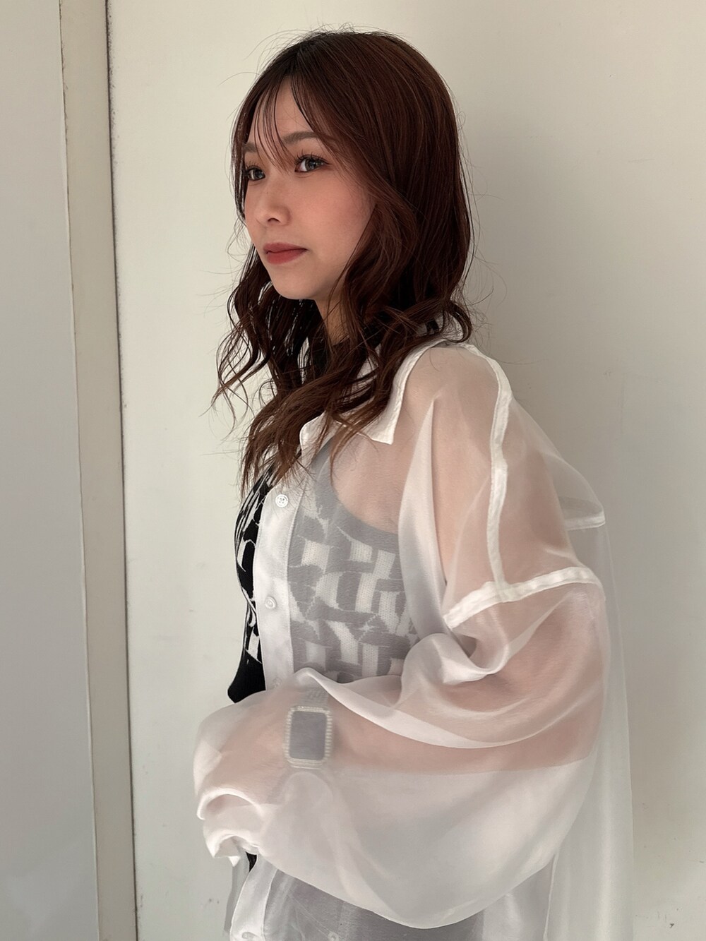 ブラック系のニット/セーター、ブラック系のデニムパンツ、ホワイト系のシャツ/ブラウスを着用したレディースの春コーディネートの5枚目の写真