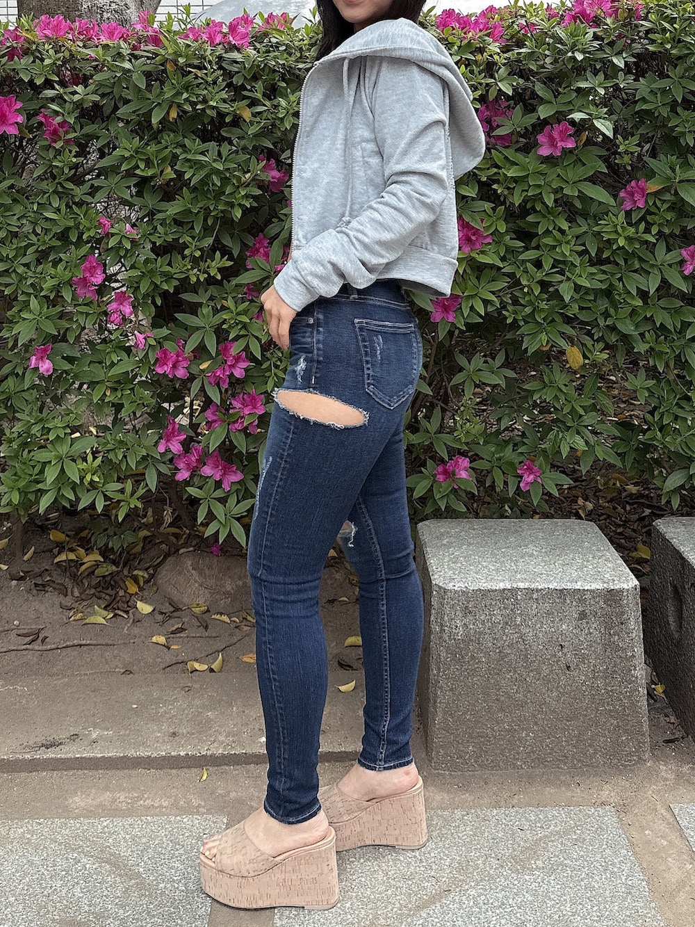 グレー系のパーカー、ブルー系のデニムパンツ、ホワイト系のサンダルを着用したレディースの春コーディネートの2枚目の写真