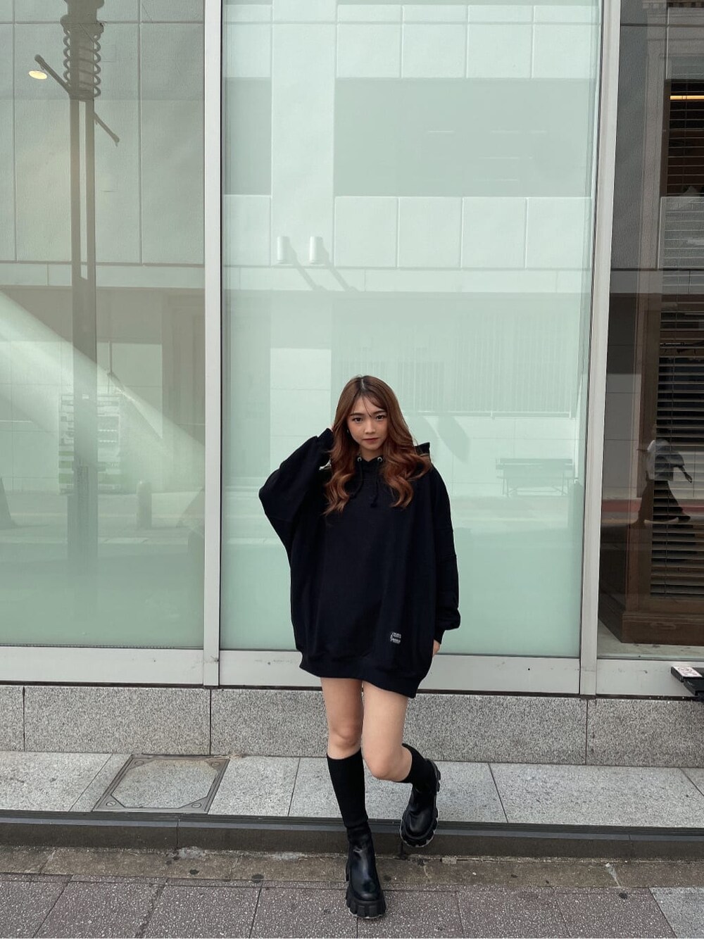 ブラック系のパーカー、ブラック系のデニムパンツ、ブラック系のブーツを着用したレディースの秋コーディネートの2枚目の写真