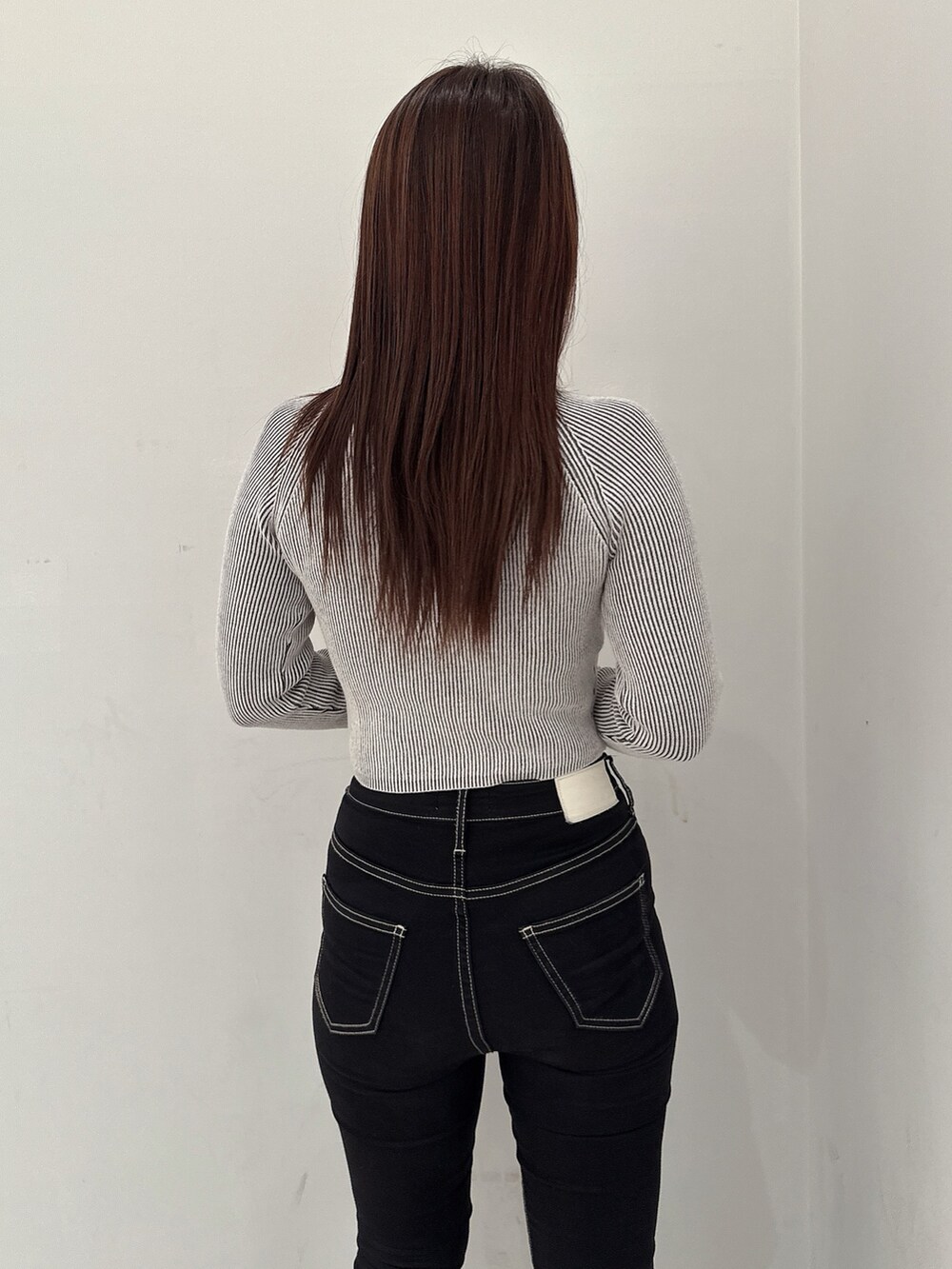 ブラック系のニット/セーター、ブラック系のデニムパンツ、ブラック系のブーツを着用したレディースの夏コーディネートの6枚目の写真