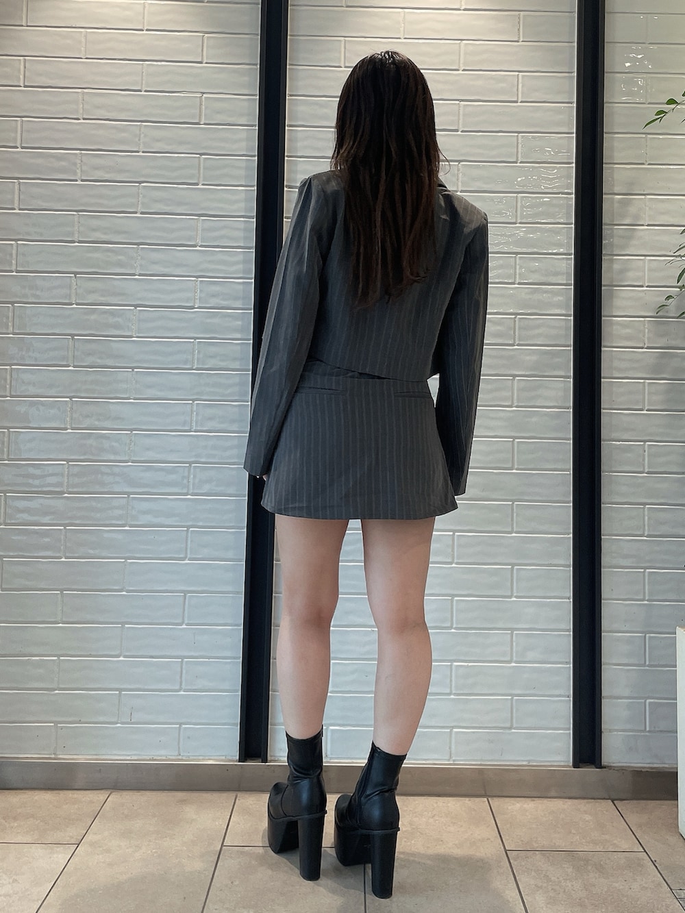 グレー系のスカート、ブラック系のブーツ、グレー系のテーラードジャケットを着用したレディースの夏コーディネートの3枚目の写真