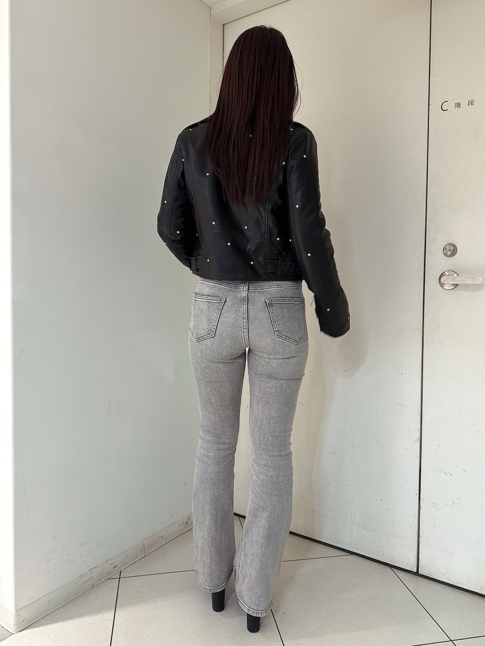 グレー系のデニムパンツ、ブラック系のブーツ、ブラック系のライダースジャケットを着用したレディースの夏コーディネートの3枚目の写真