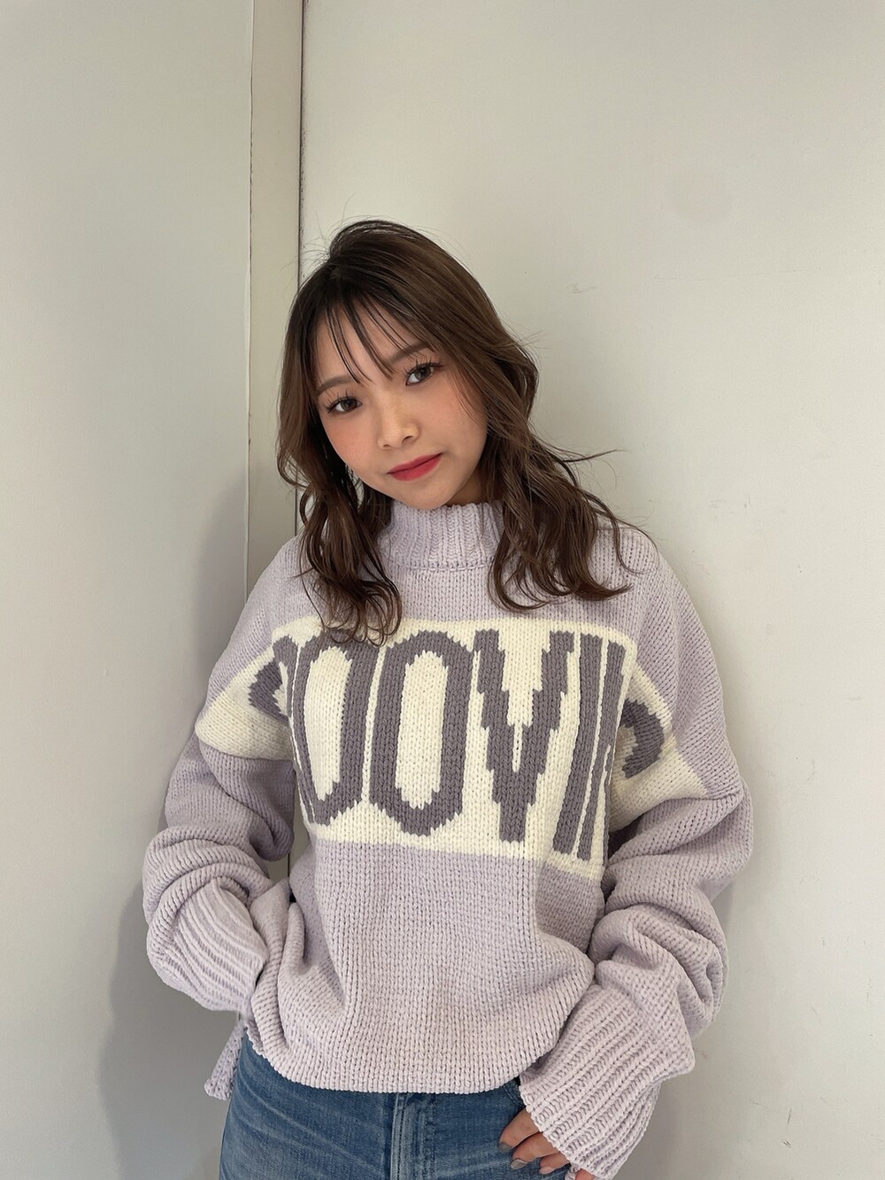 パープル系のニット/セーター、ブルー系のデニムパンツ、ホワイト系のパンプスを着用したレディースの冬コーディネートの4枚目の写真