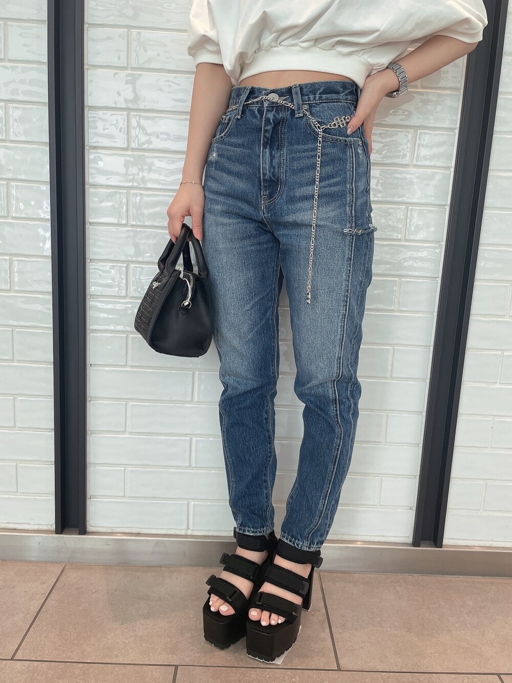 ブルー系のデニムパンツ、ブラック系のハンドバッグ、ブラック系のサンダルを着用したレディースの春コーディネートの6枚目の写真