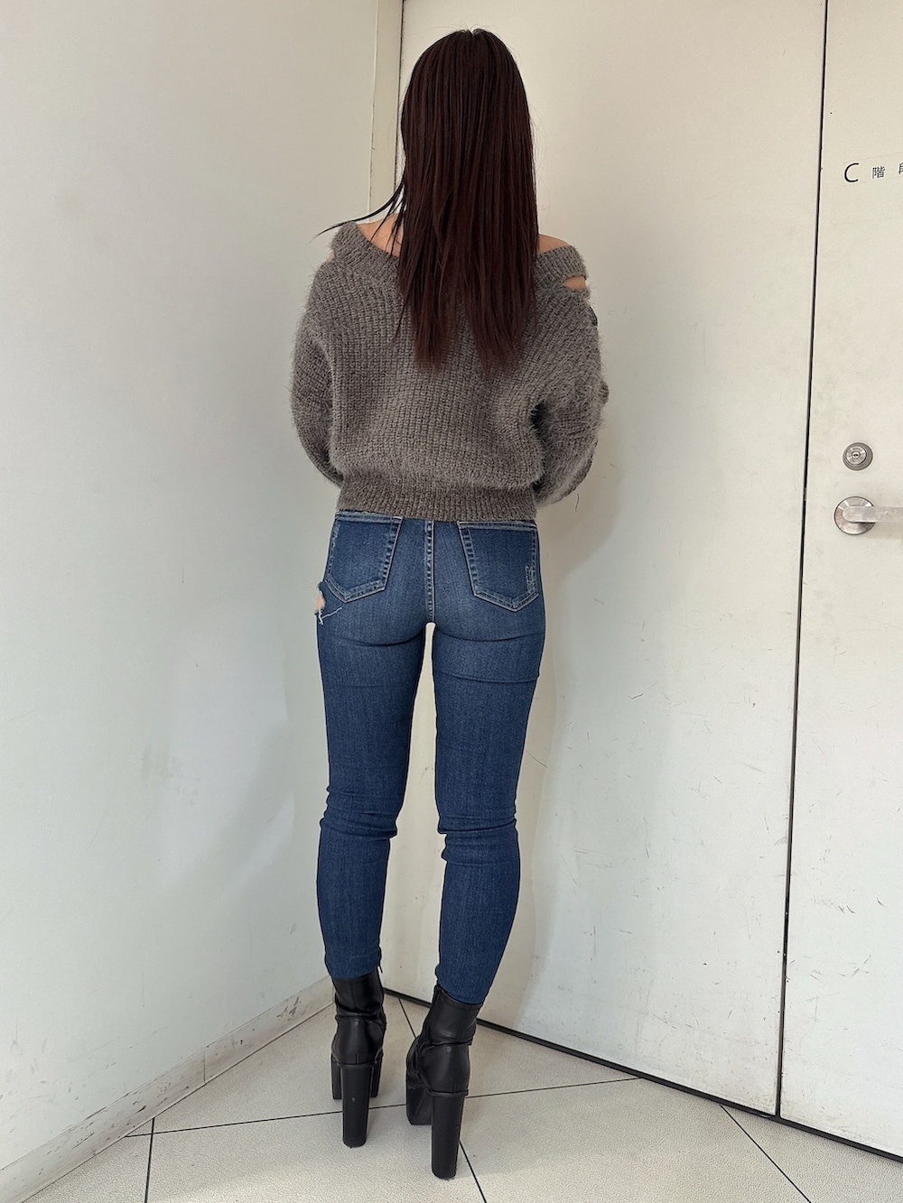 ブルー系のデニムパンツ、ブラック系のブーツ、グレー系のニット/セーターを着用したレディースの秋コーディネートの3枚目の写真