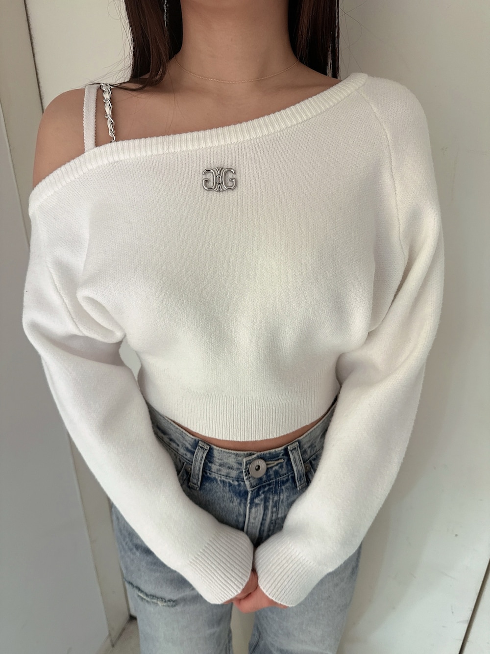 ホワイト系のニット/セーター、ブルー系のデニムパンツ、ホワイト系のパンプスを着用したレディースの冬コーディネートの7枚目の写真