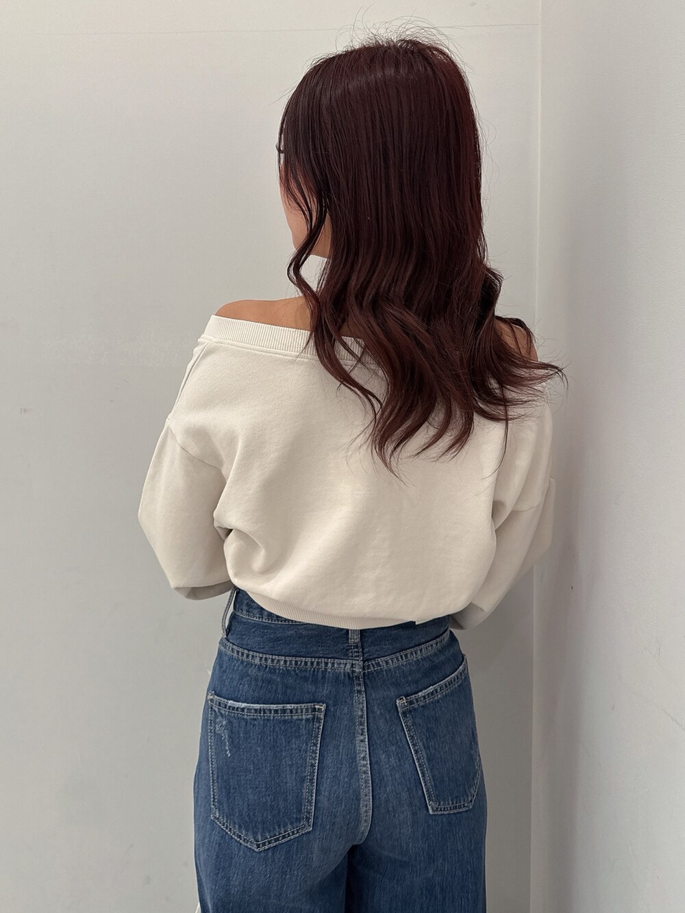 ホワイト系のスウェット、ブルー系のデニムパンツ、ブラック系のブーツを着用したレディースの秋コーディネートの5枚目の写真