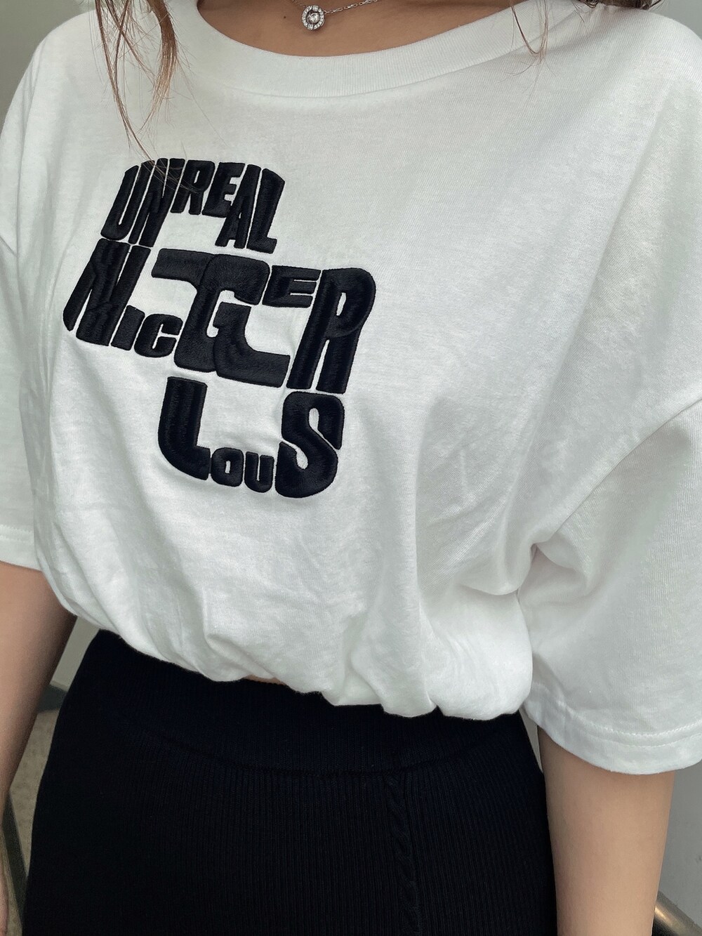 ブラック系のスカート、ブラック系のハンドバッグ、ホワイト系のTシャツ/カットソーを着用したレディースの夏コーディネートの7枚目の写真