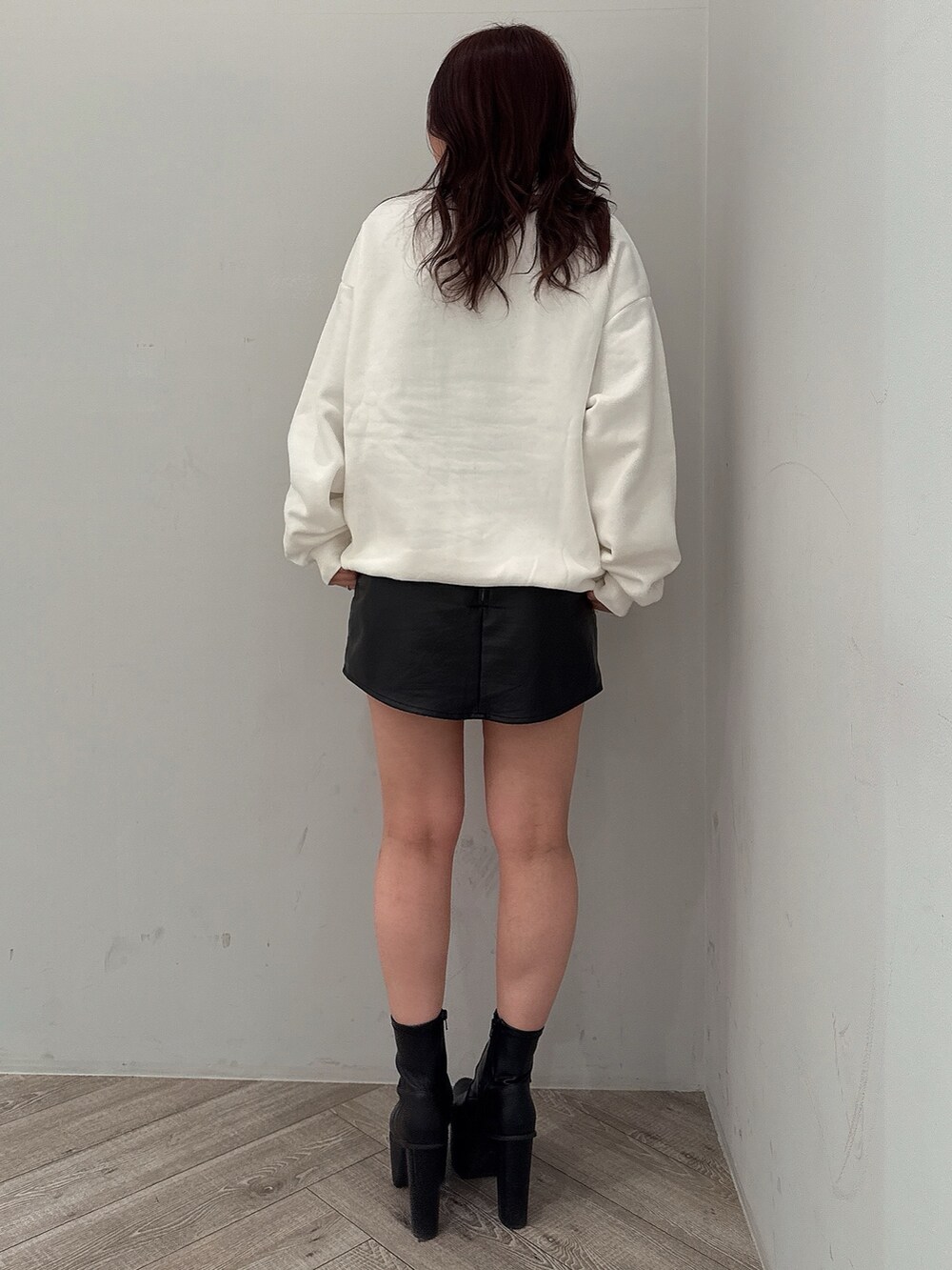 ブラック系のスカート、ブラック系のブーツ、ホワイト系のスウェットを着用したレディースの冬コーディネートの3枚目の写真