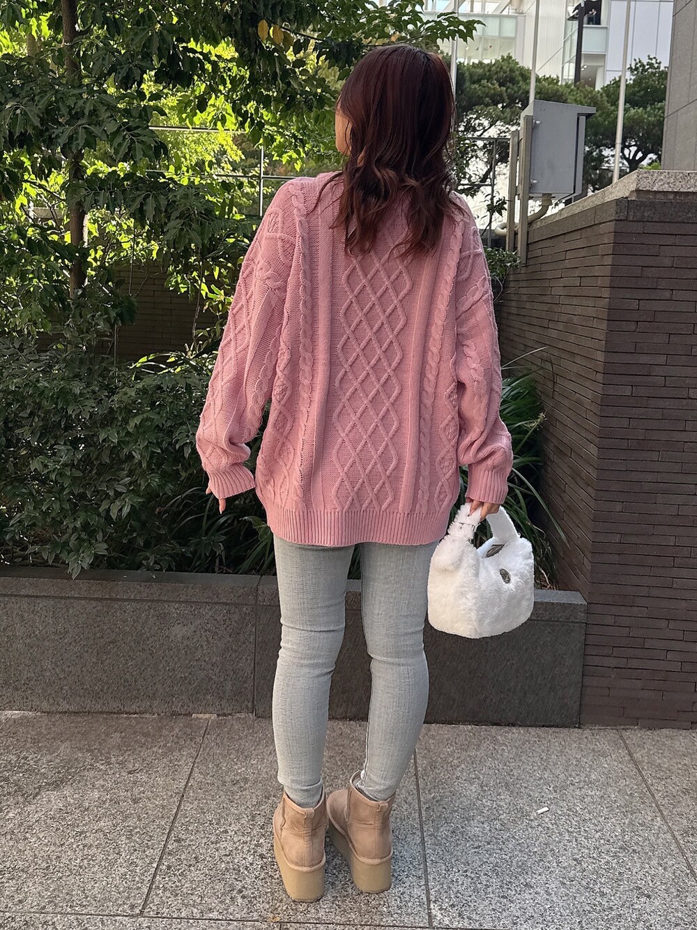 ピンク系のニット/セーター、ホワイト系のハンドバッグ、ブルー系のデニムパンツを着用したレディースの秋コーディネートの3枚目の写真