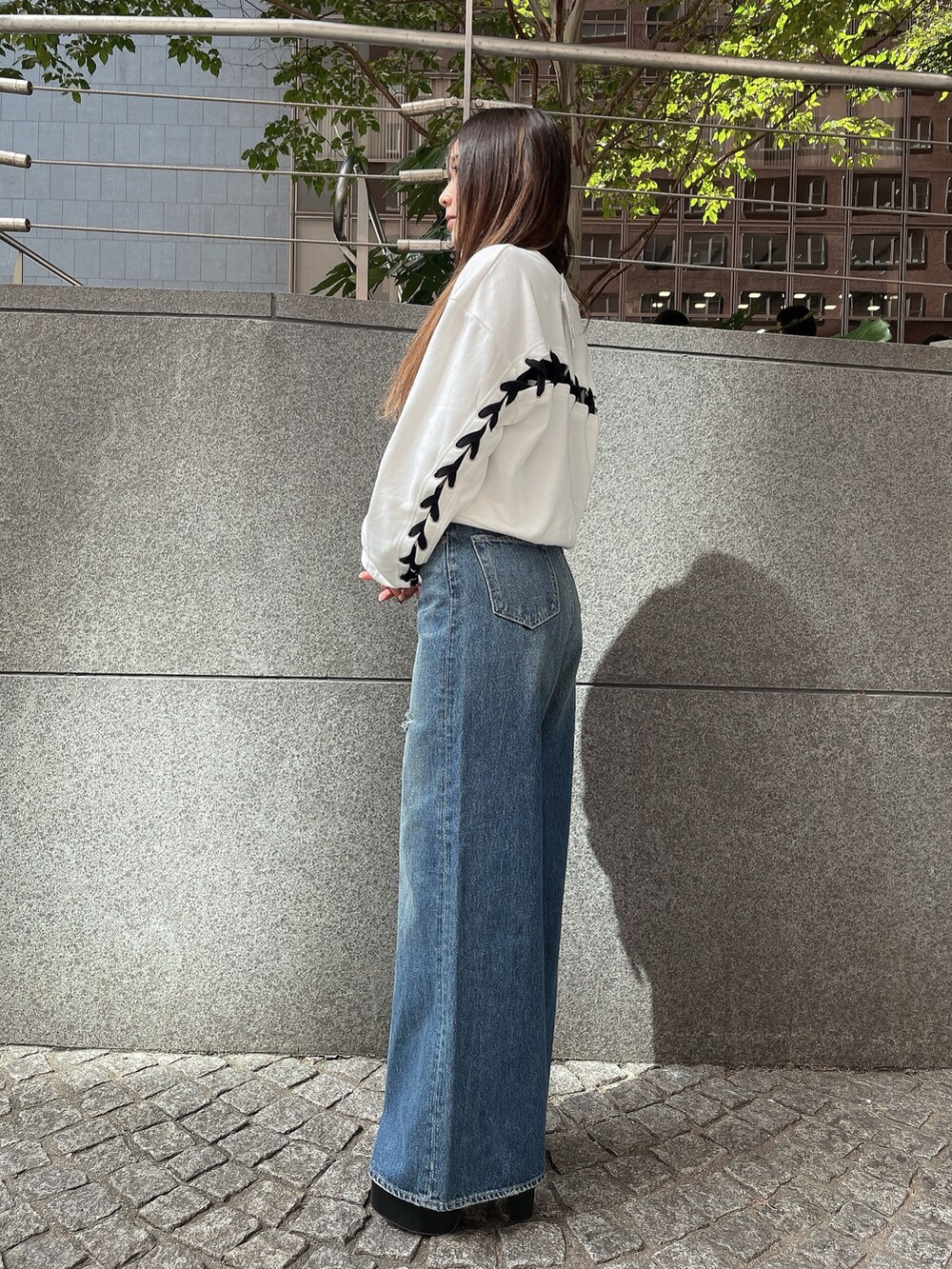 ブラック系のブーツ、ブラック系のデニムパンツ、ホワイト系のスウェットを着用したレディースの秋コーディネートの2枚目の写真