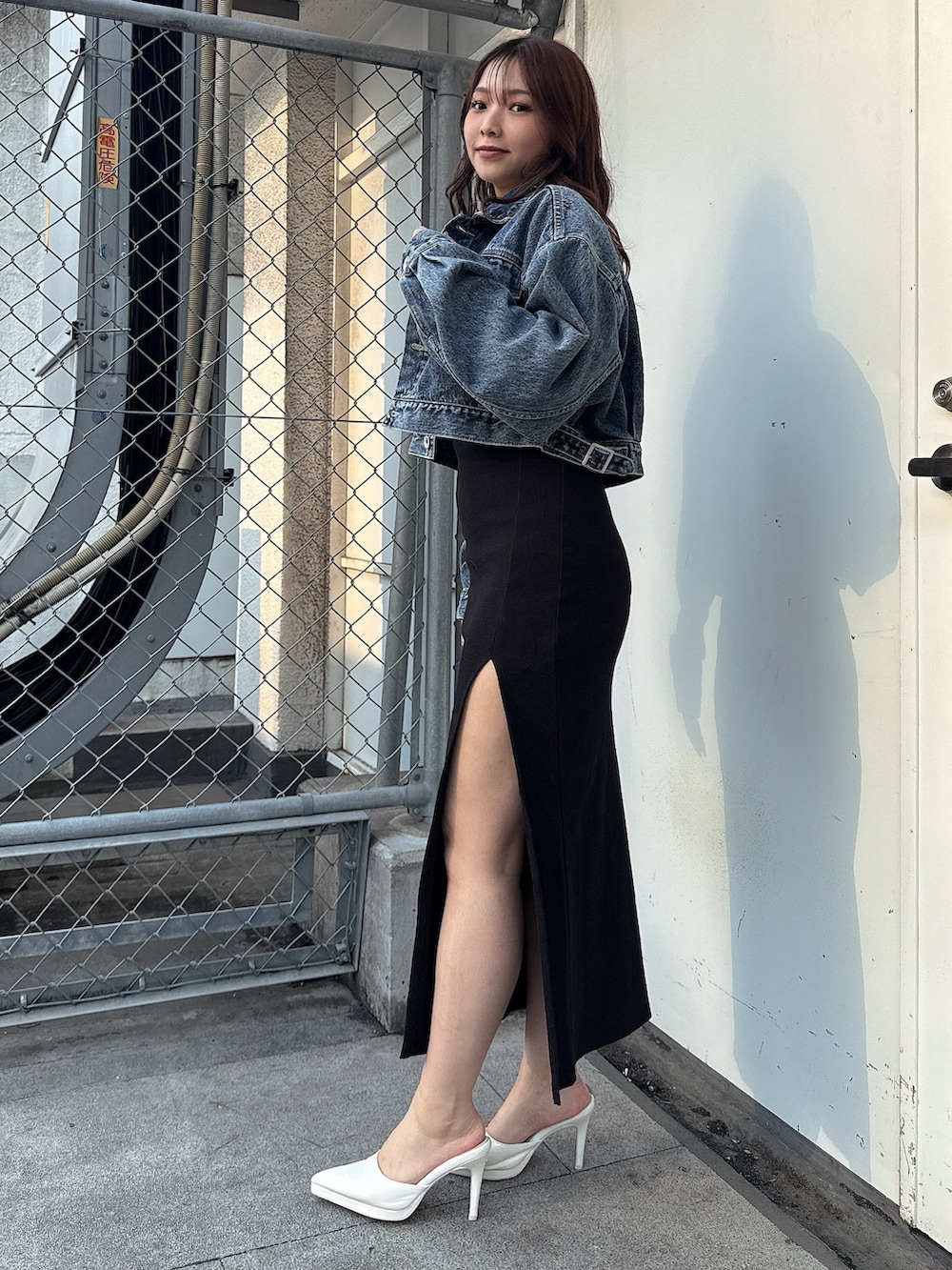 ブラック系のワンピース、ホワイト系のパンプス、ブルー系のデニムジャケットを着用したレディースの春コーディネートの2枚目の写真