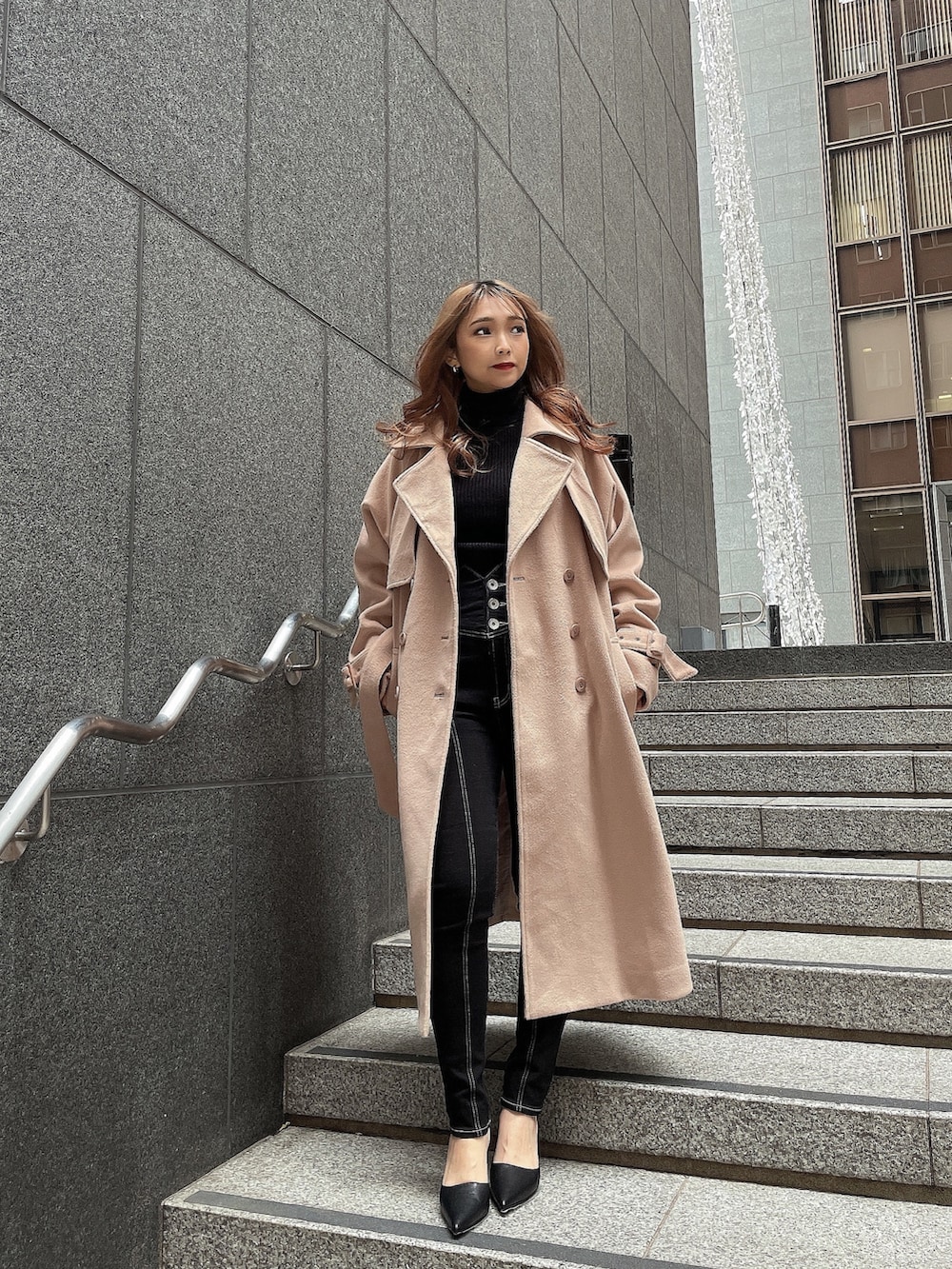 ブラック系のニット/セーター、ベージュ系のトレンチコート、ブラック系のデニムパンツを着用したレディースの冬コーディネートの2枚目の写真